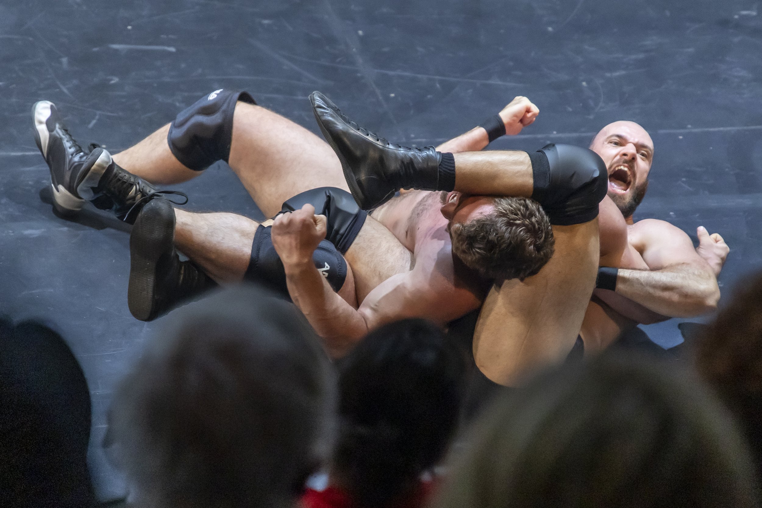 Two men wrestling on a mat, with one man pinning the other down in a sports match.