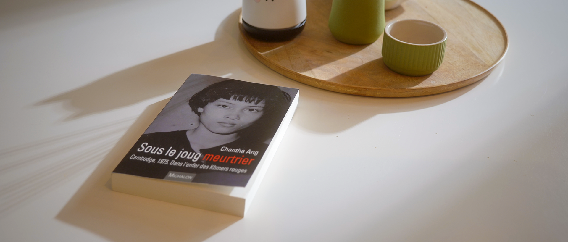 Livre en noir et blanc posé sur une table, avec la photo d'une femme sur la couverture, et le titre "Sous le joug meurtrier".