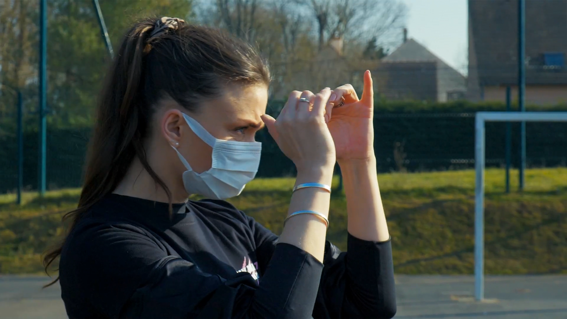 Une femme portant un masque sanitaire est en garde et se prépare à lancer un coup de poing lors d'un entraînement à l'extérieur.