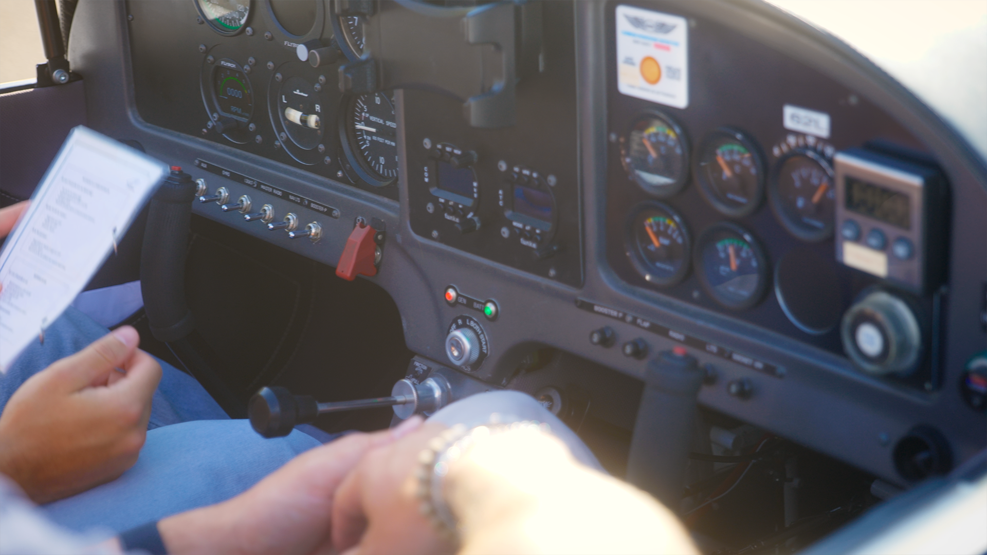 Gros plan d'un cockpit d'un avion au sol avec plusieurs instruments et gauges. Une personne tient un document dans une main.