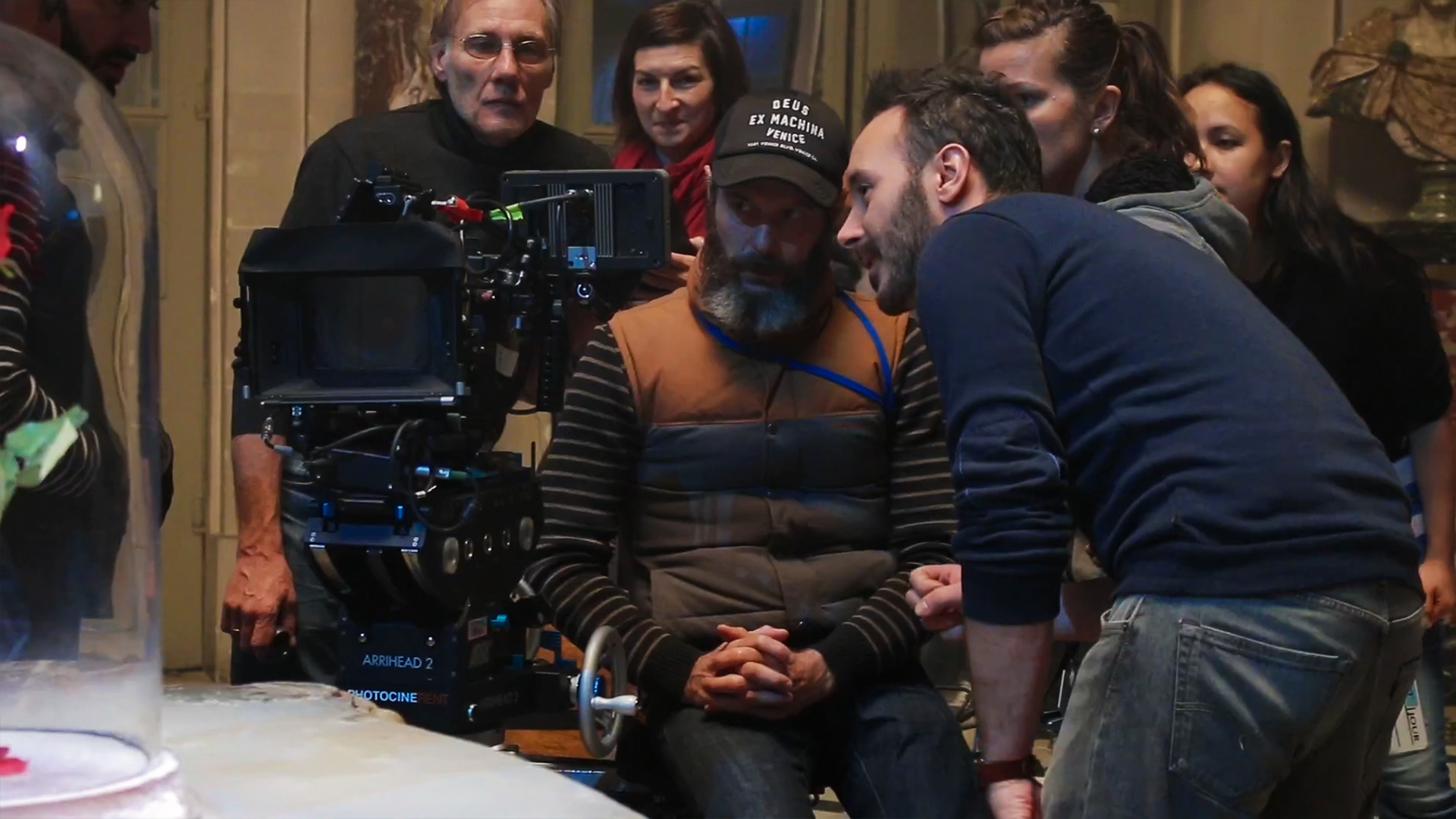 Groupe de personnes autour d'une caméra de tournage, en intérieur.