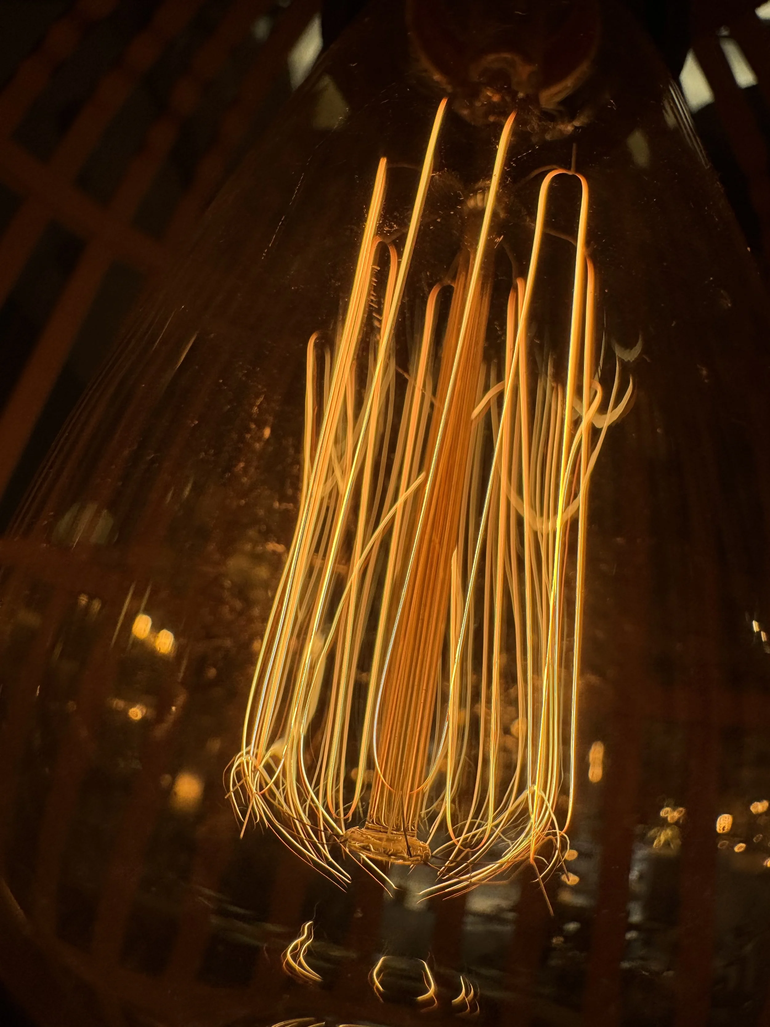 Close-up of a vintage-style filament light bulb with glowing orange filaments inside a glass enclosure.