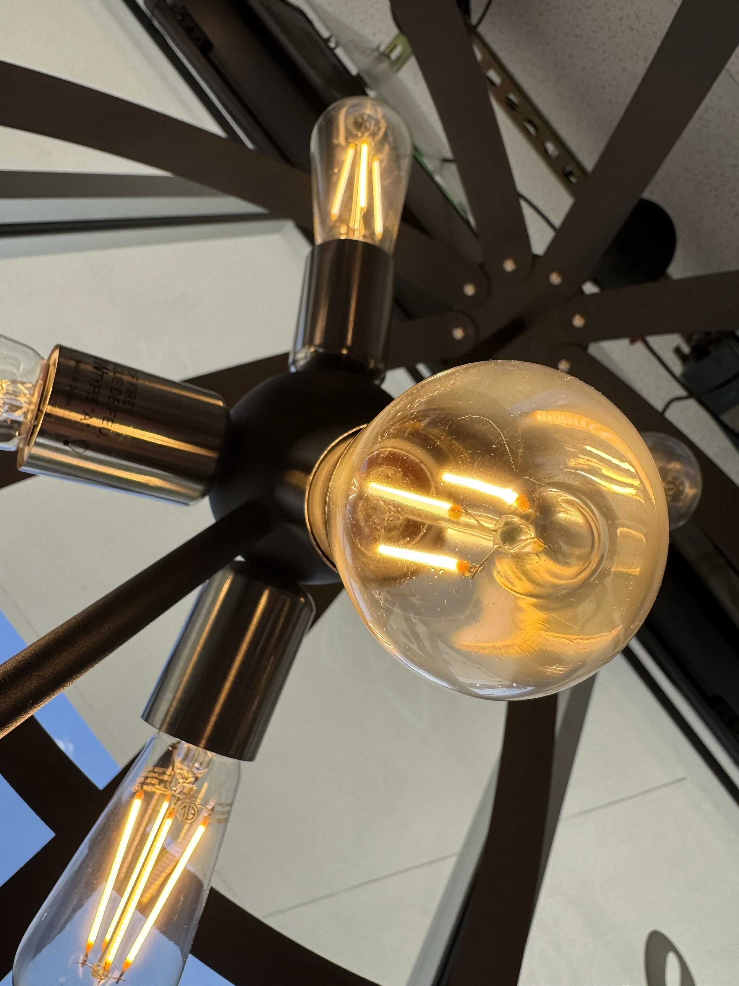 Close-up view of a modern chandelier with multiple exposed vintage-style filament light bulbs mounted on a ceiling.