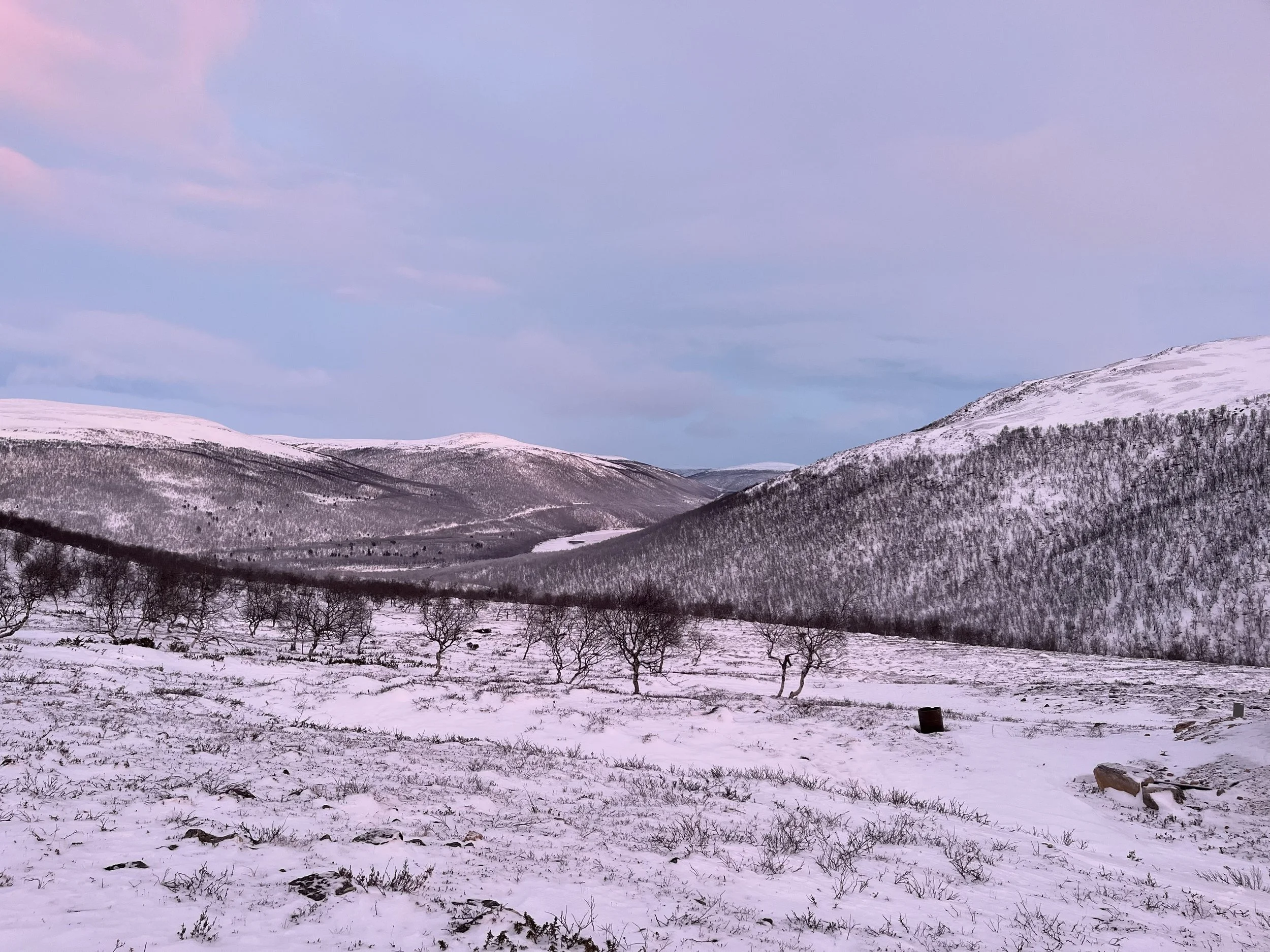 Luminen vuoristoalue, lumipeitteiset mäet ja selkeä taivaskuva, osa pilviä näkyvissä