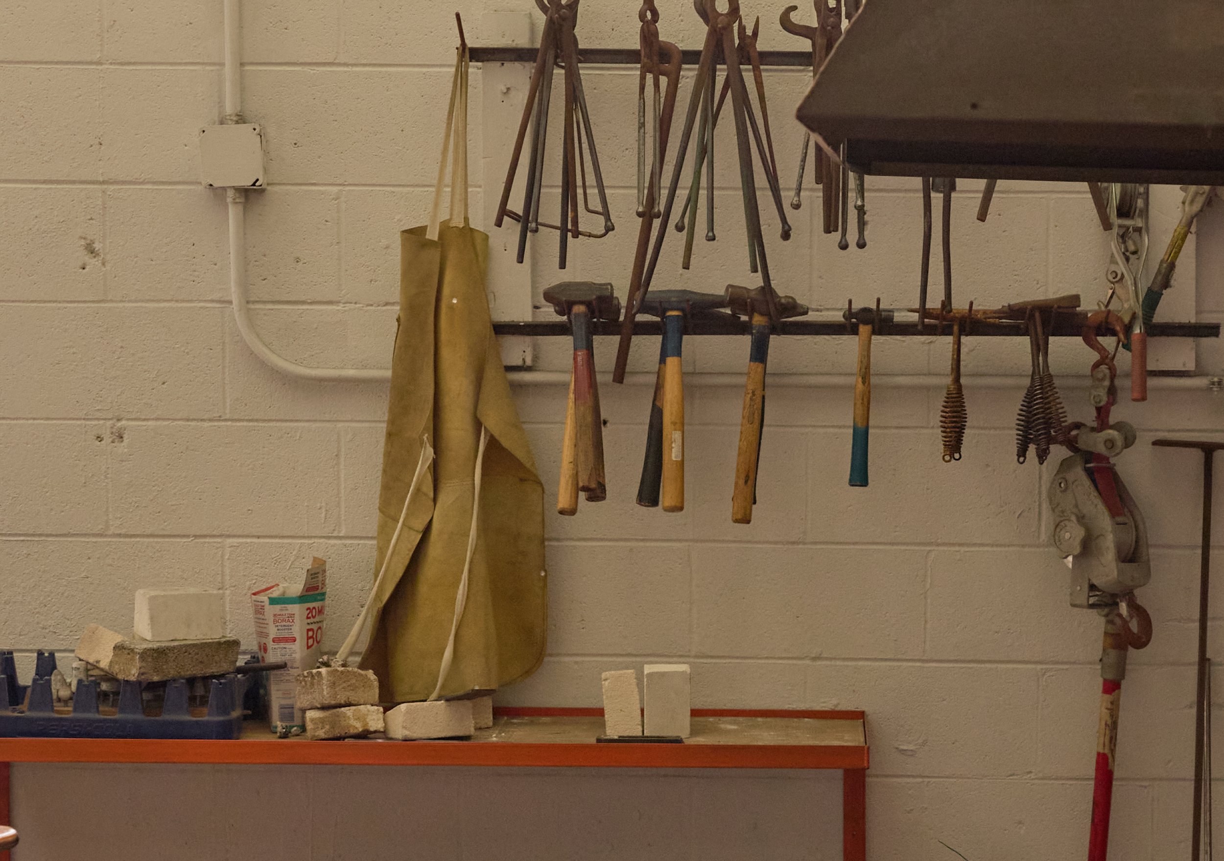 Hand tools and aprons hanging on a workshop wall, representing hands-on making at Village of Industry & Art.