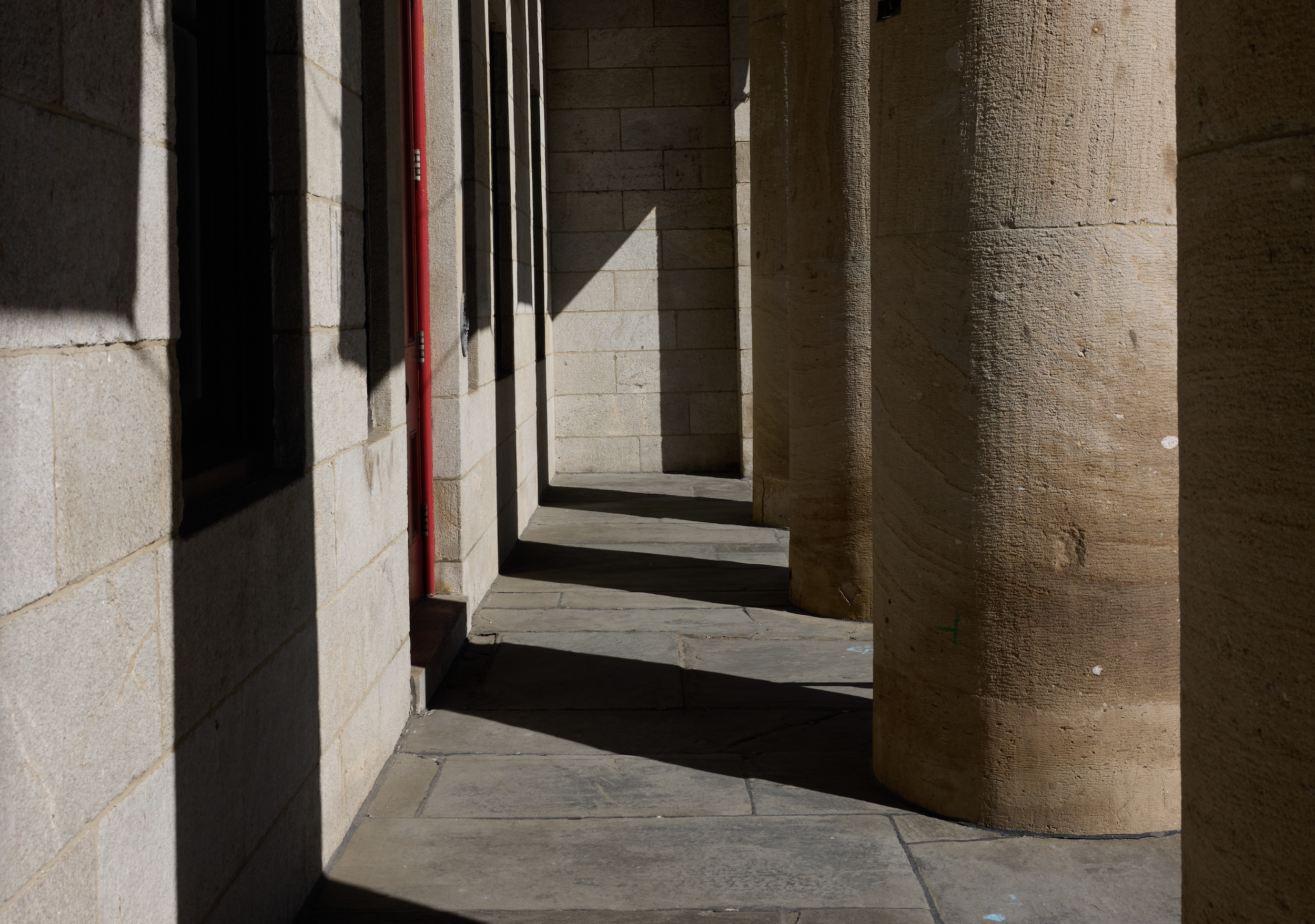 An atypical view of the building's Broad Street facade, seeing the columns in a retreating line and the heavy shadows they create on the ground and walls behind them.
