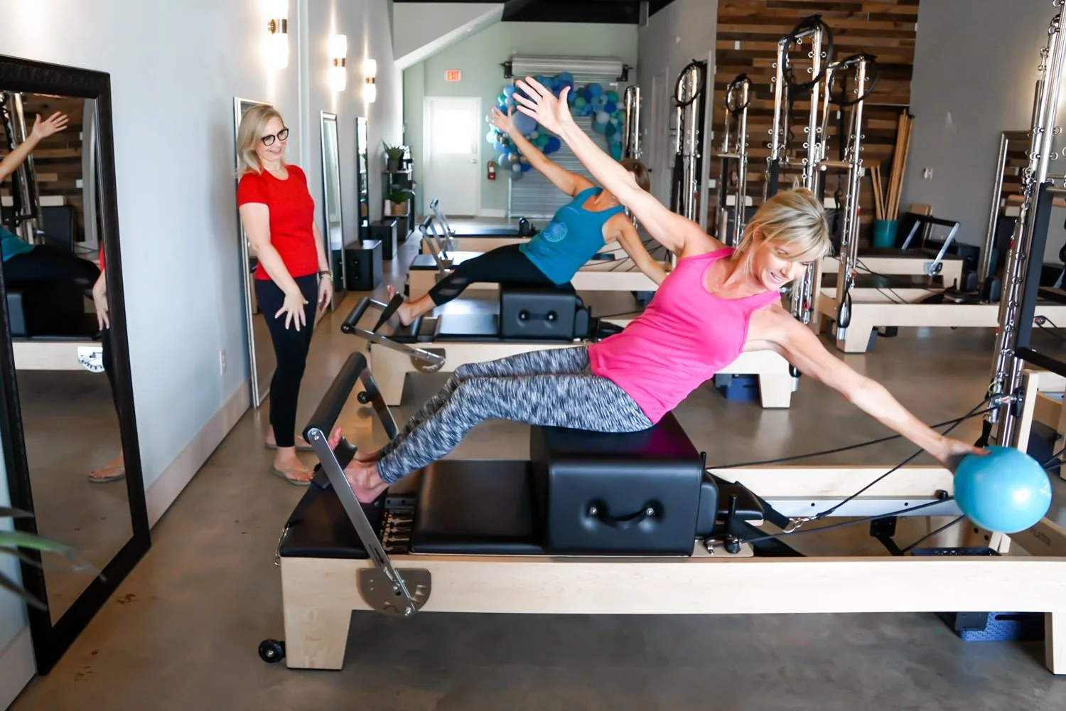 Two women exercising on Pilates reformers while a trainer watches at Body & Soul Pilates in Gluckstadt, MS