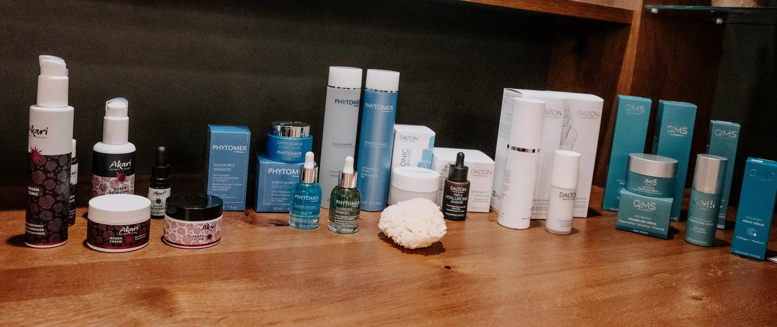 Verschiedene Hautpflegeprodukte, darunter Cremes, Seren und Fläschchen, auf einem Holzoberfläche.