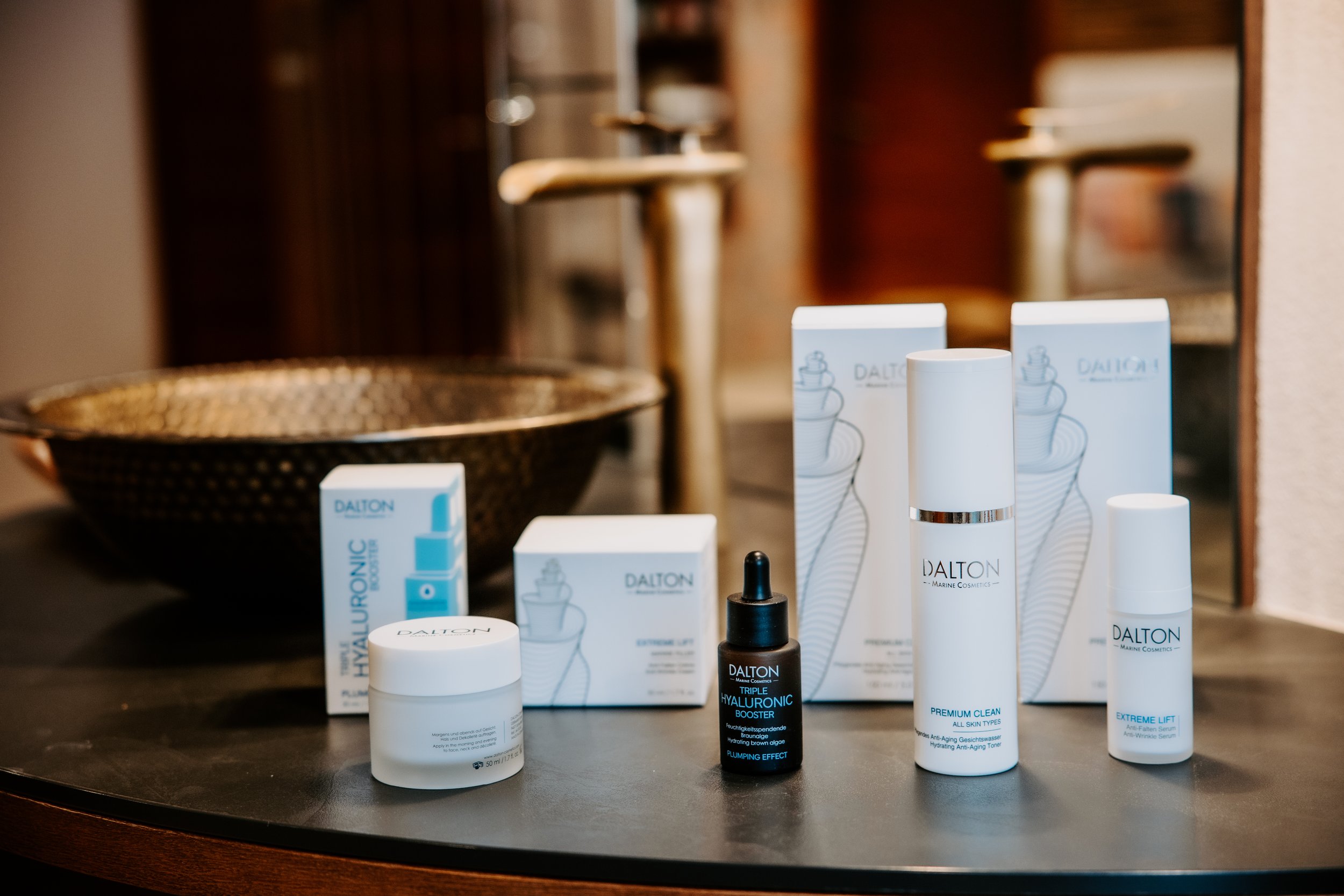 Hautpflegeprodukte von Dalton auf einem schwarzen Tisch, vor einem großen Spiegel.