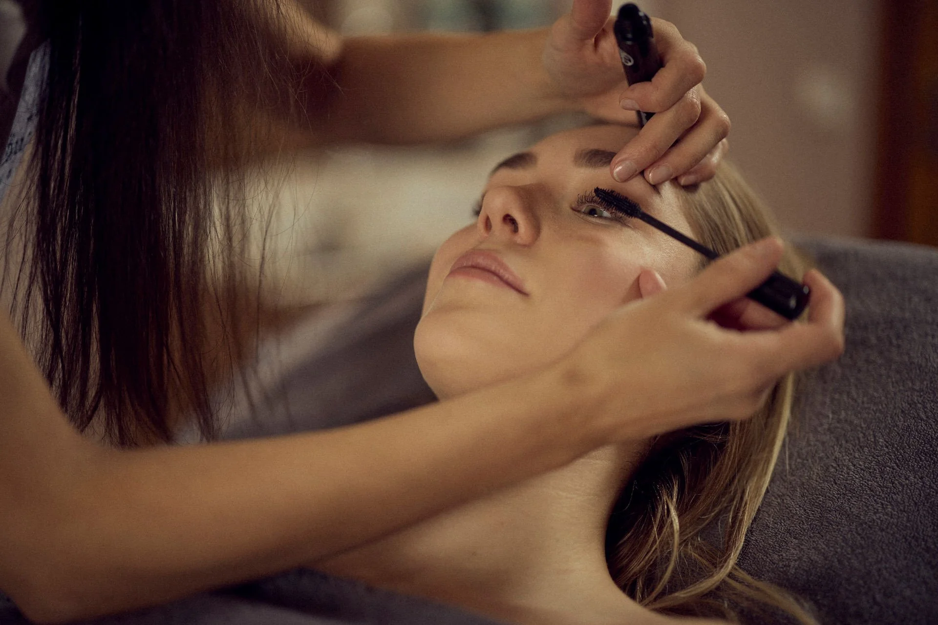 Frau lässt sich im Kosmetikstudio die Wimpern schminken.