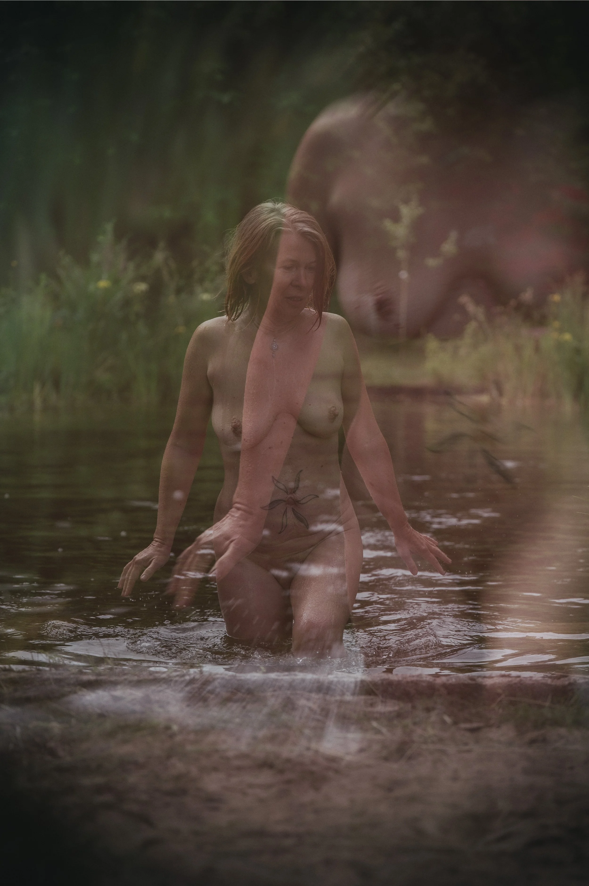 Eine nackte Frau, die in einem Fluss steht, im Freien mit Bäumen im Hintergrund, und eine doppelte, überlagerte Kopfaufnahme im rechten oberen Bereich.