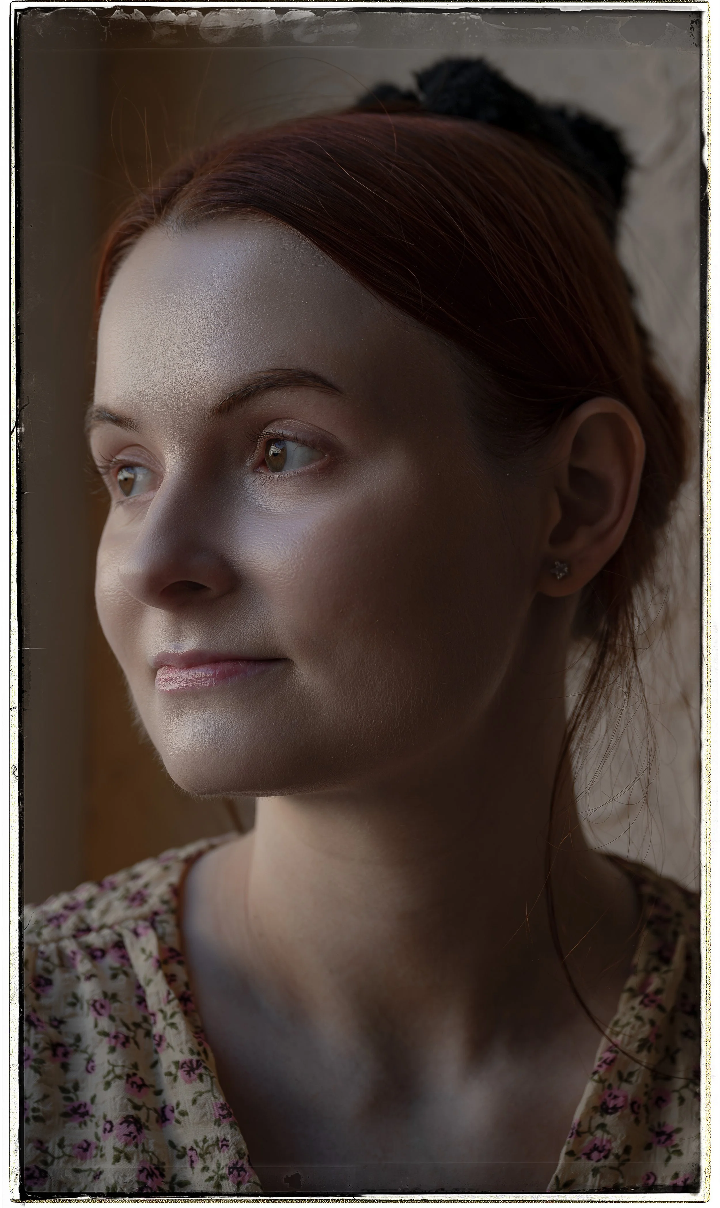 Nahaufnahme eines lächelnden jungen Mädchens mit roten Haaren, das aus einem Fenster schaut.