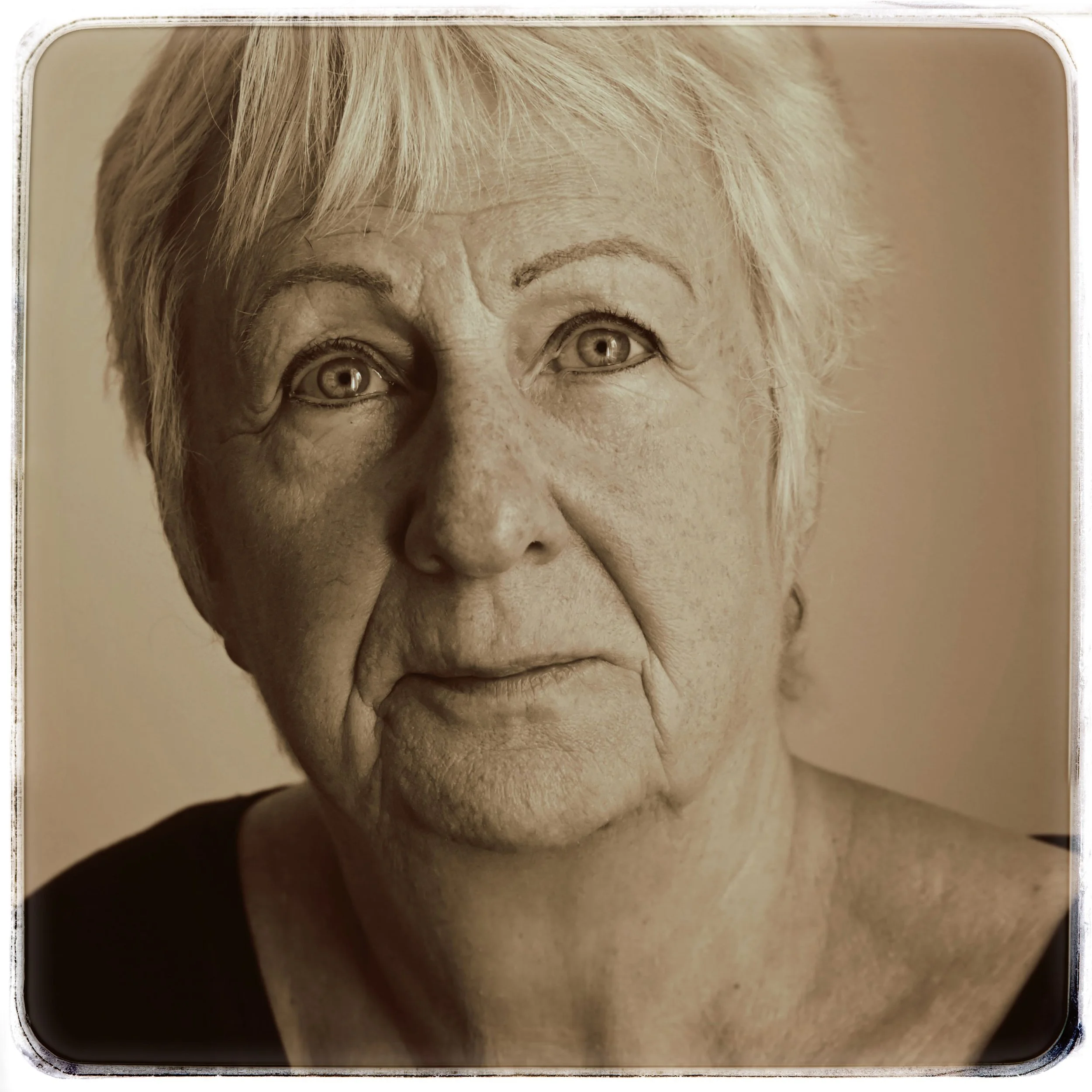 Schwarz-Weiß-Porträt einer älteren Frau mit kurzen, hellen Haaren, blauen Augen und nachdenklichem Ausdruck.