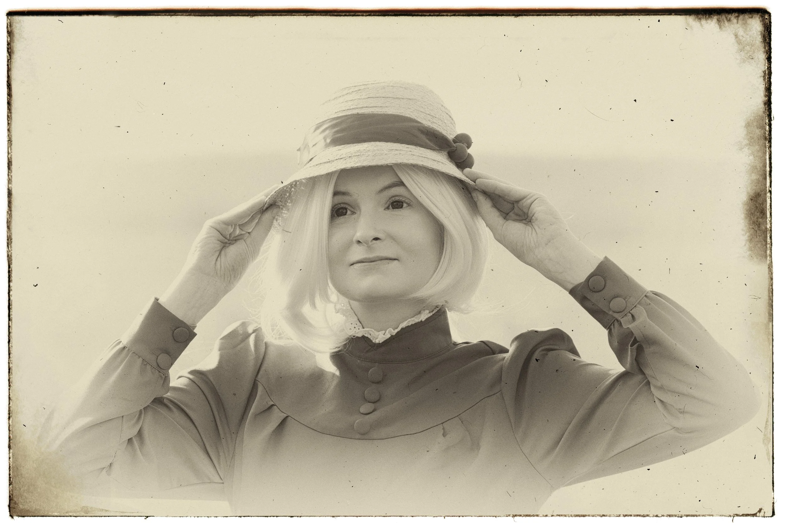 Frau mit Hut, die die Krempe des Huts hält, in einem Vintage-Stil fotografiert.