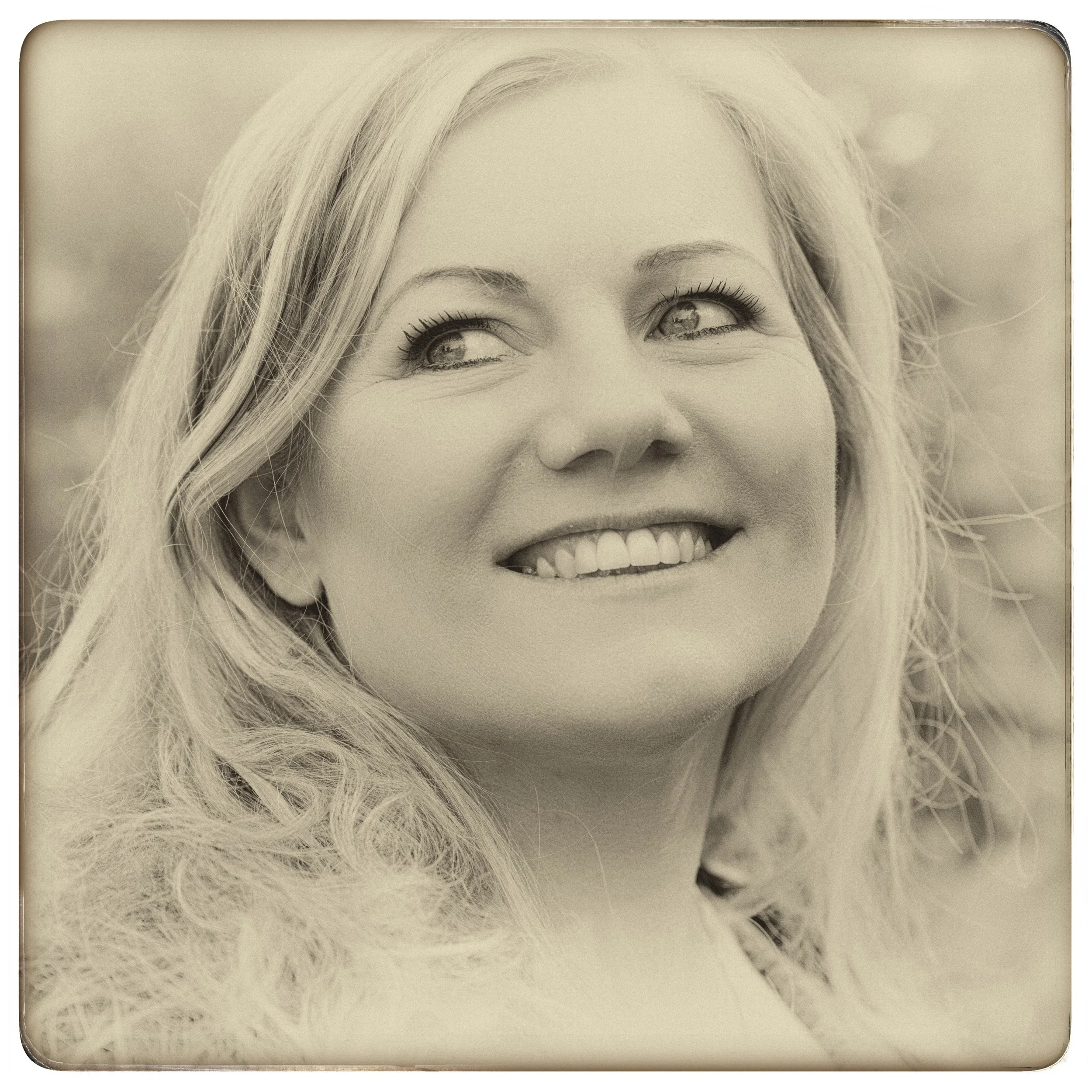 Lächelnde Frau mit lockigem, blonden Haar, outdoors, in Sepia-Ton.