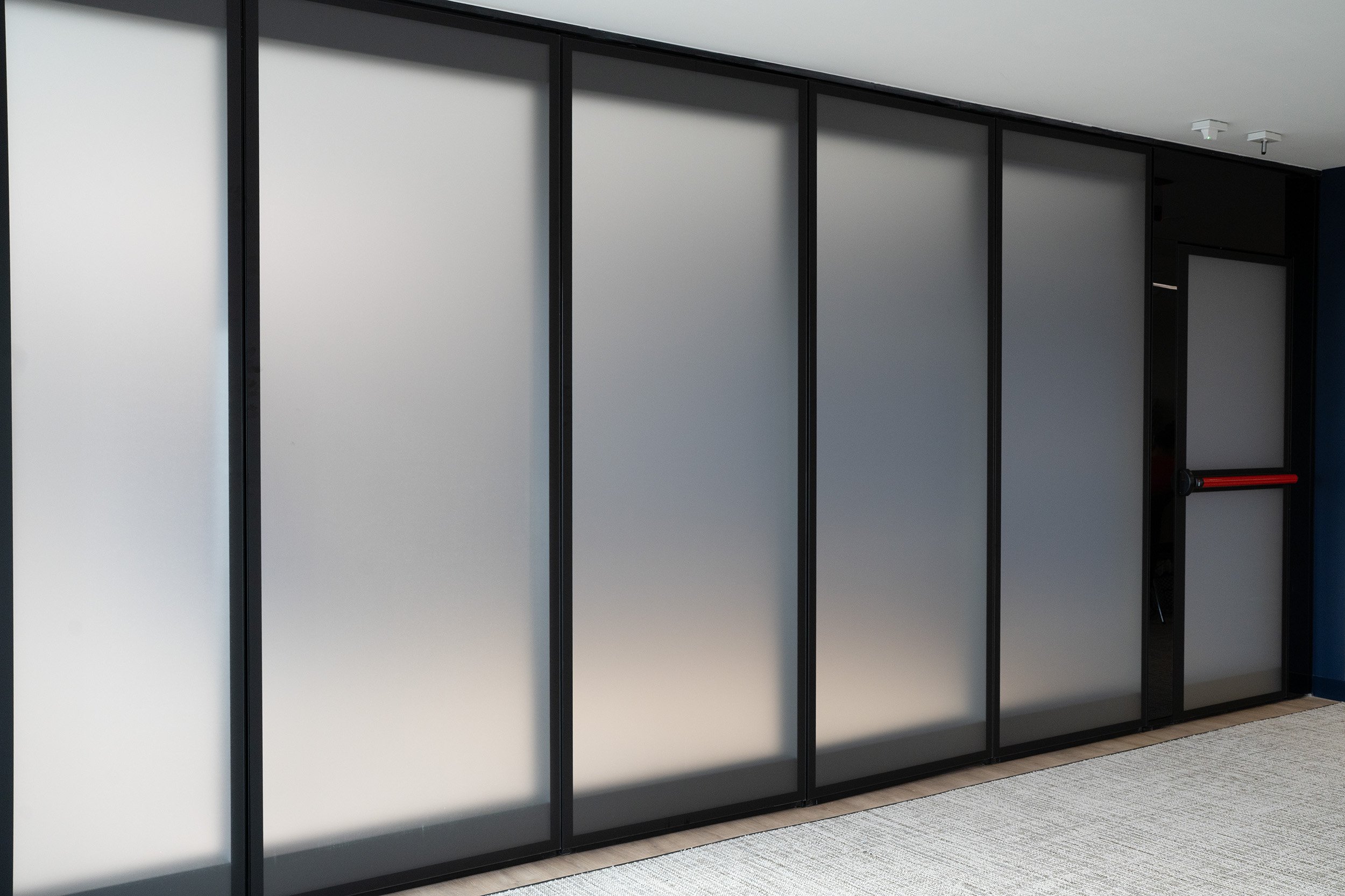 Modern office space with frosted glass sliding doors and black frames.