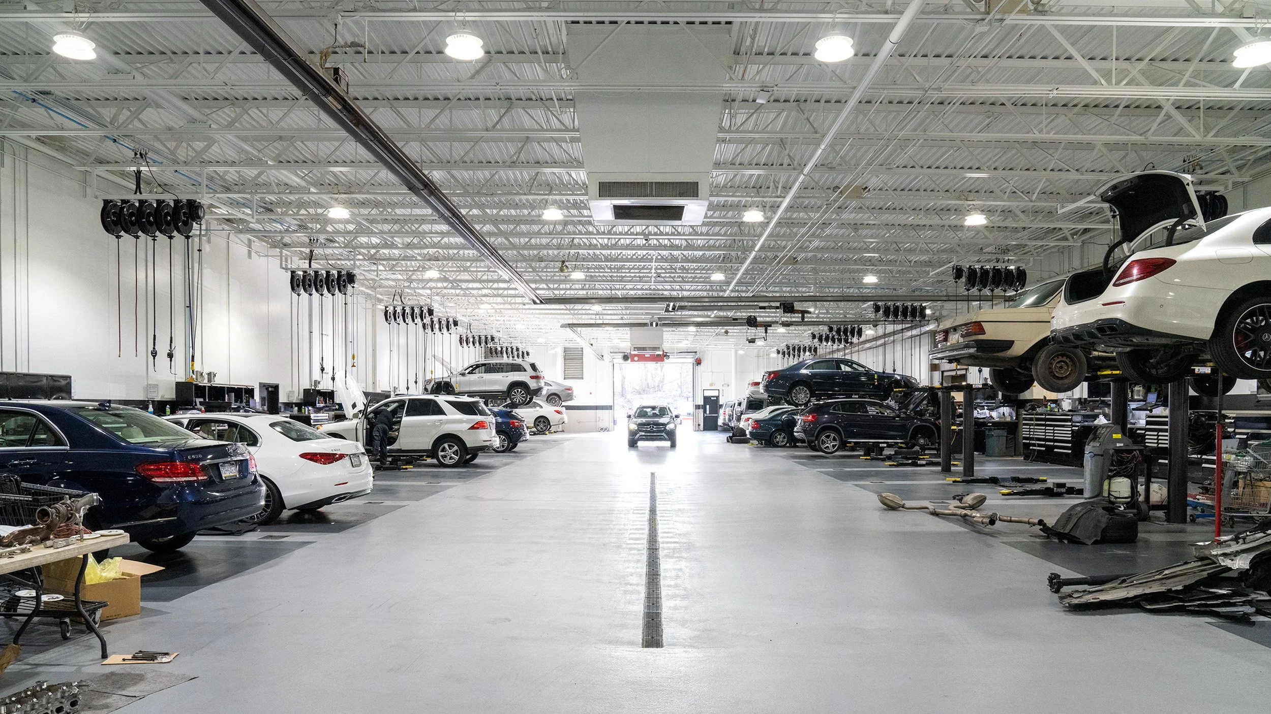 Exterior view of Mercedes-Benz dealership with several cars parked outside, including a white car prominently in front, and signage indicating Mercedes-Benz of Lehigh Valley during twilight.