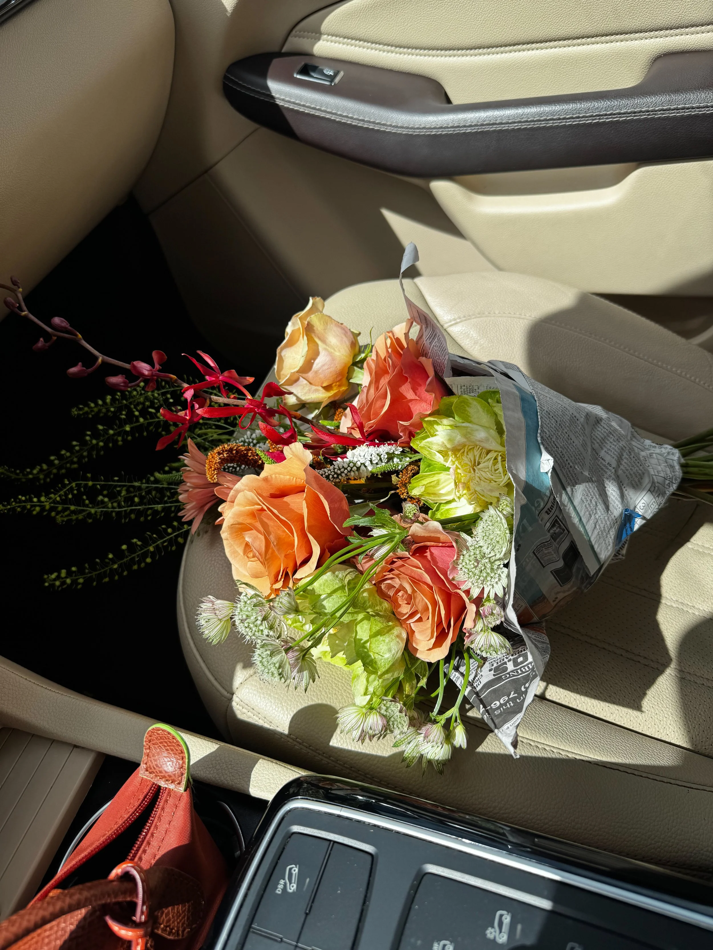 Bouquet of colorful flowers resting on a beige car seat.