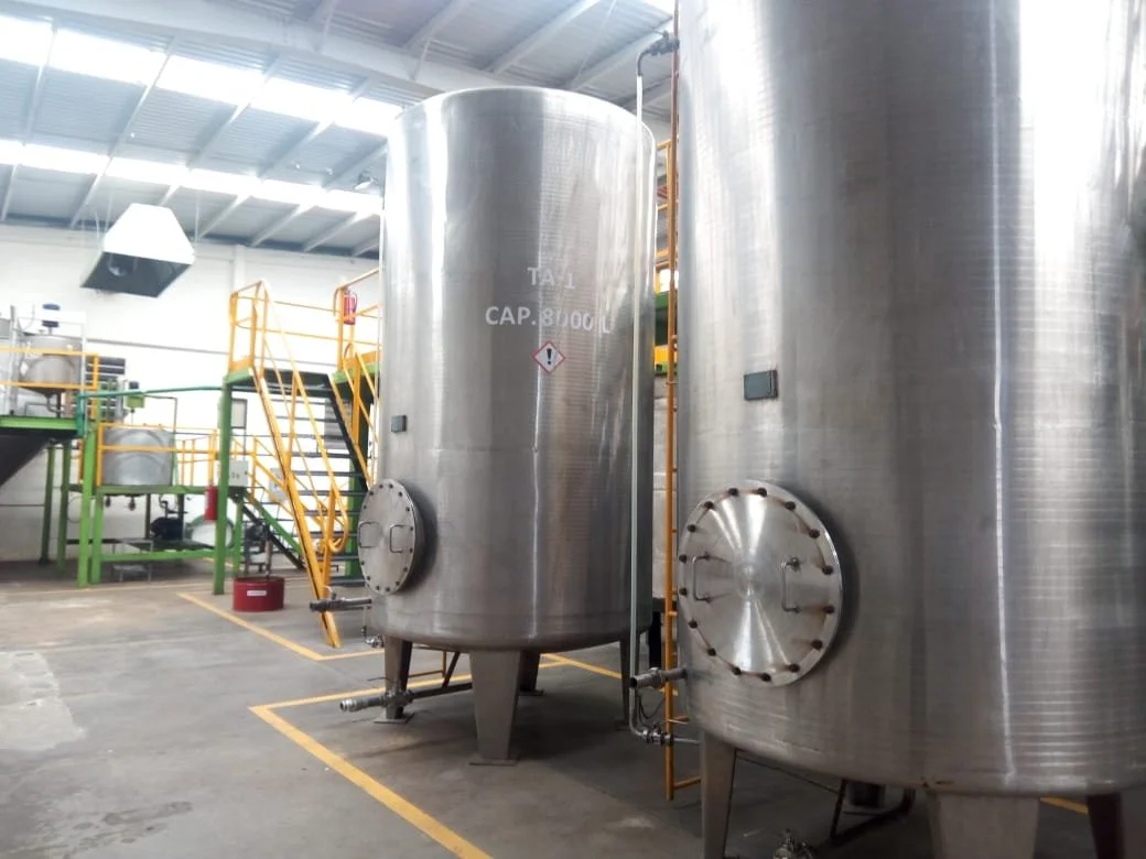 Two large stainless steel industrial tanks in a factory setting.