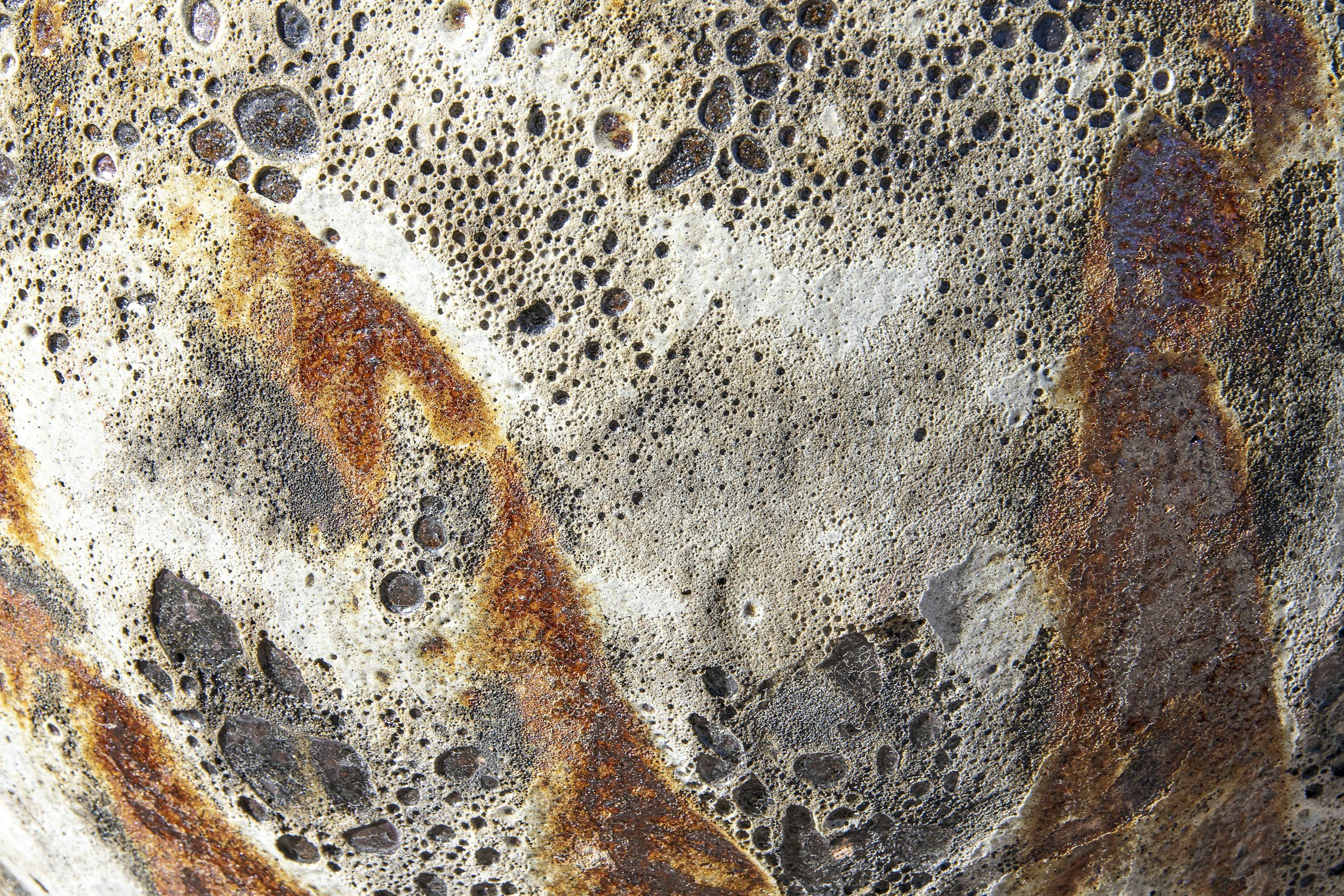 Close-up of a steaming cup of coffee with frothy bubbles on top, showing a mix of dark brown and lighter beige foam.