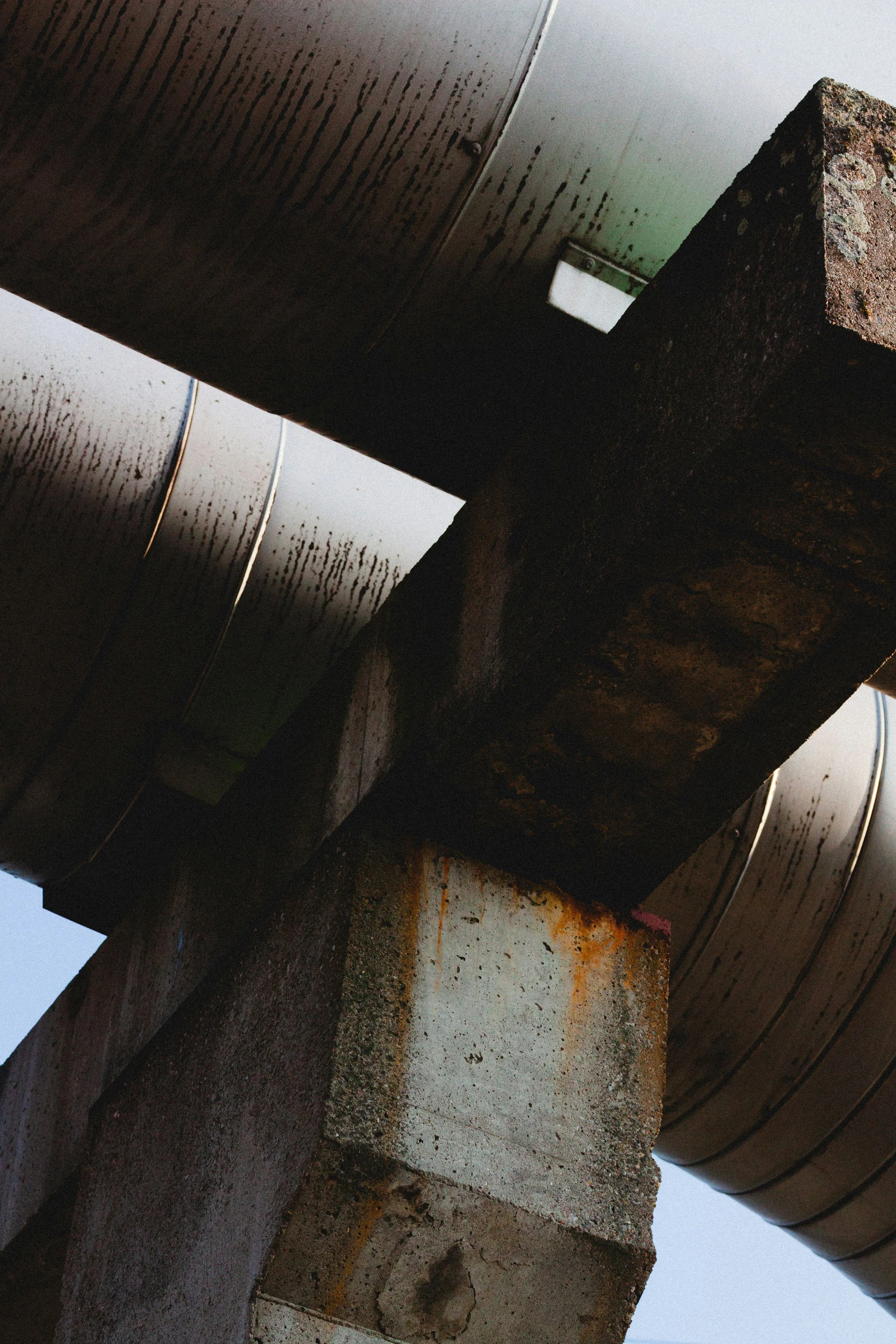 Close-up of a large metal pipe supported by rusted concrete blocks.