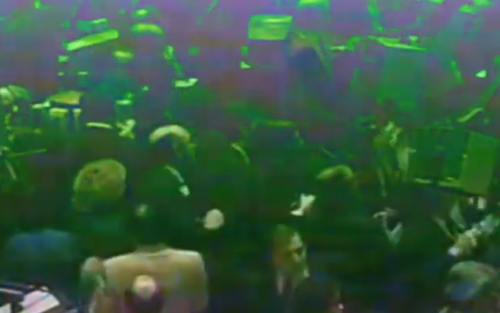 People gathered in a crowded indoor space with a green-colored overlay.