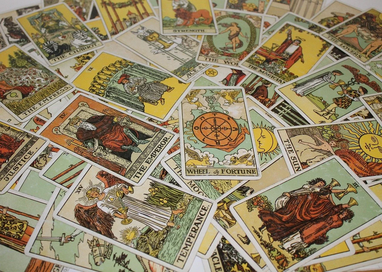 A spread of various Tarot cards, including The Empress, The Emperor, Wheel of Fortune, Justice, Temperance, and The Sun, laid out on a surface.