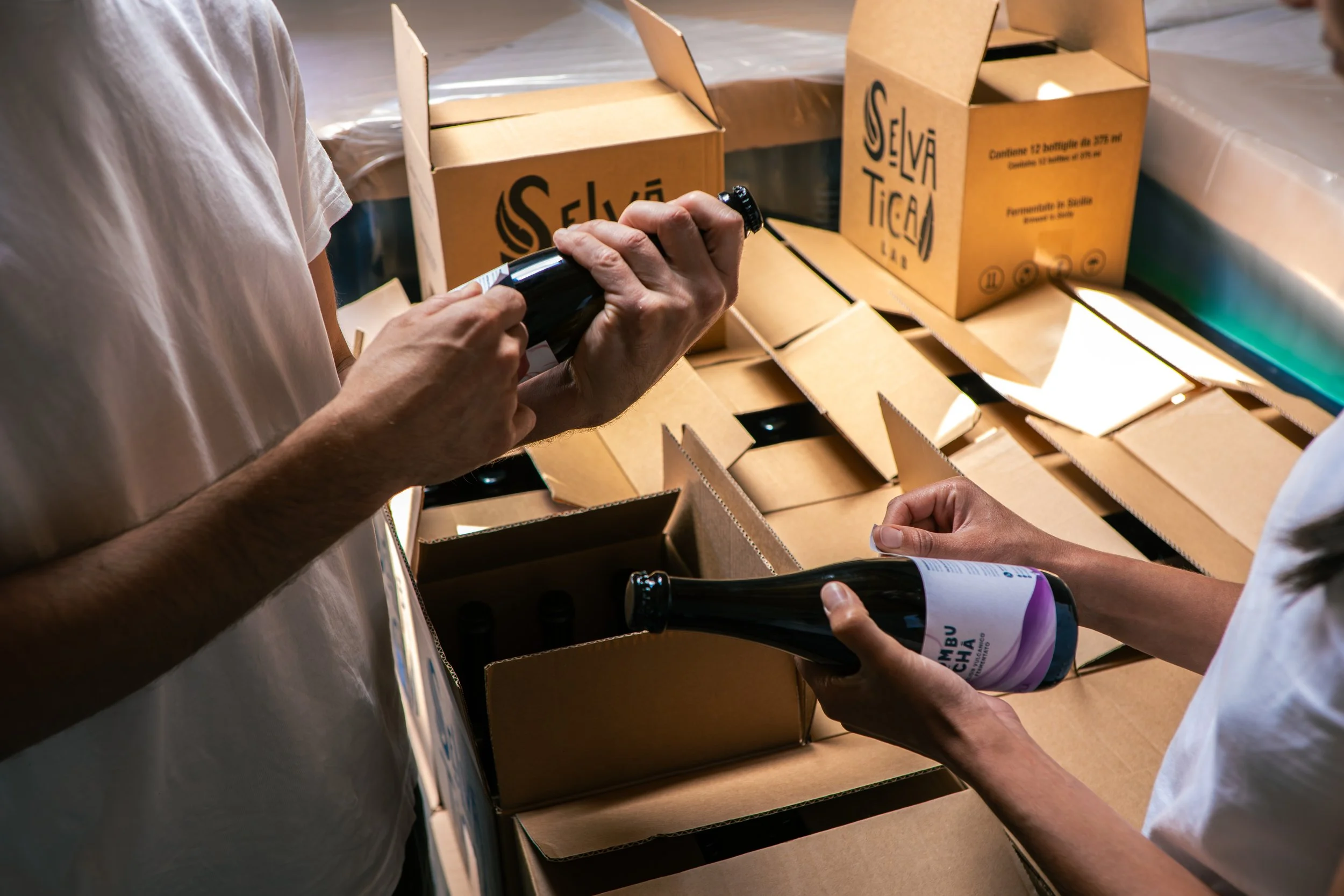 Persone che imbottigliano bottiglie di vino in scatole di cartone.