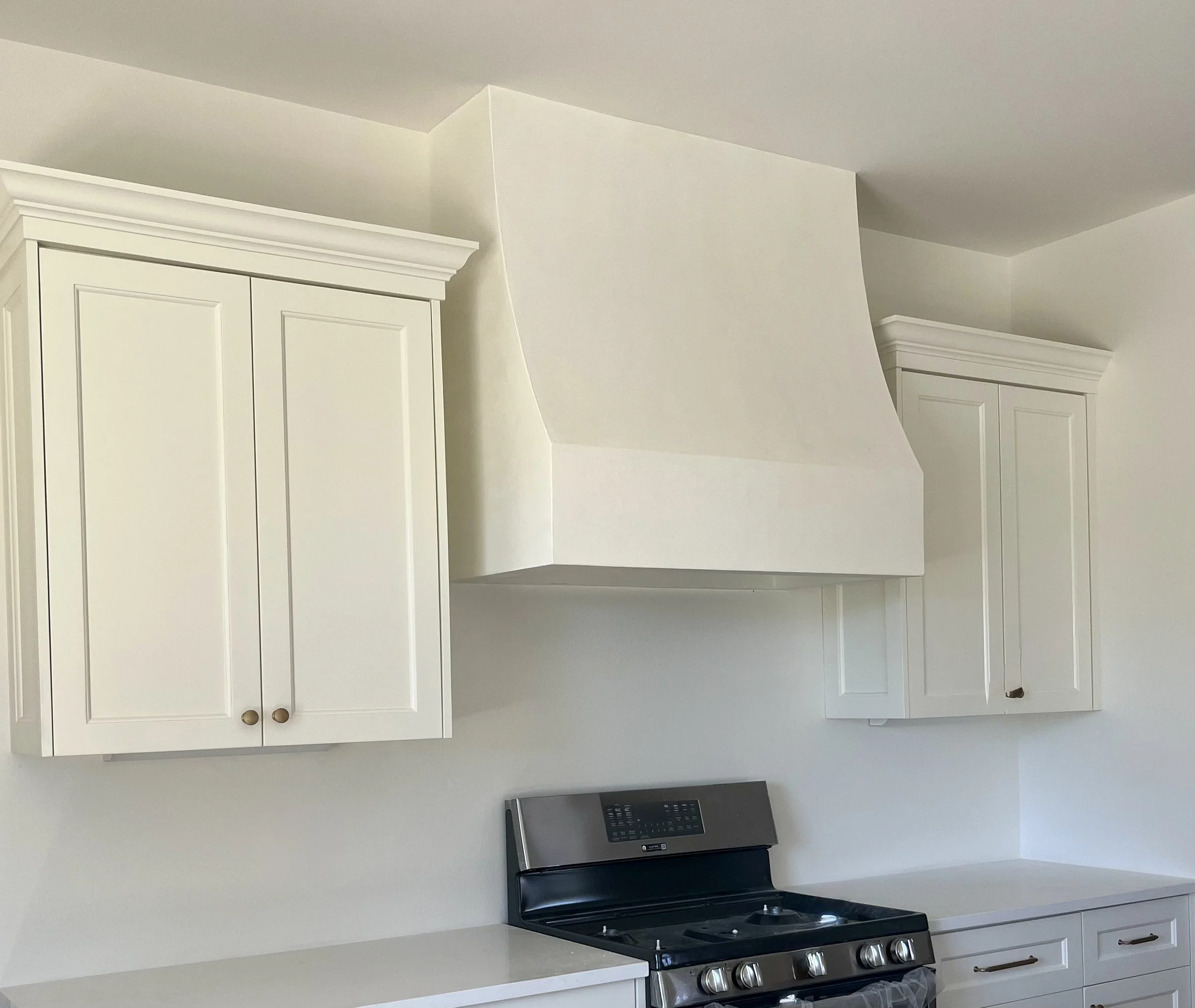 Kitchen with white cabinets, a range hood, and a stainless steel stove.