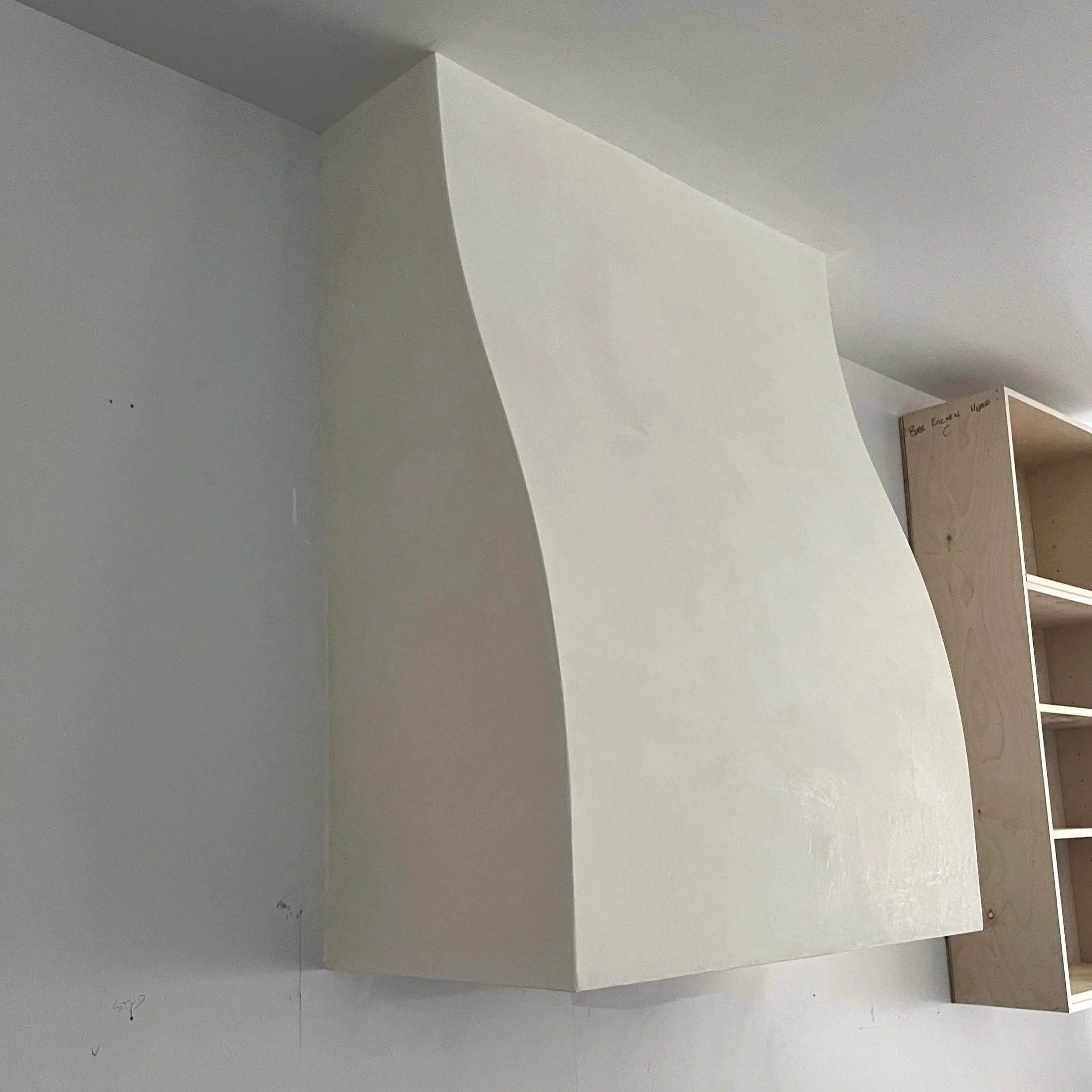 A white, curved piece of foam or cardboard leaning against a wall in a room with wooden shelving units.