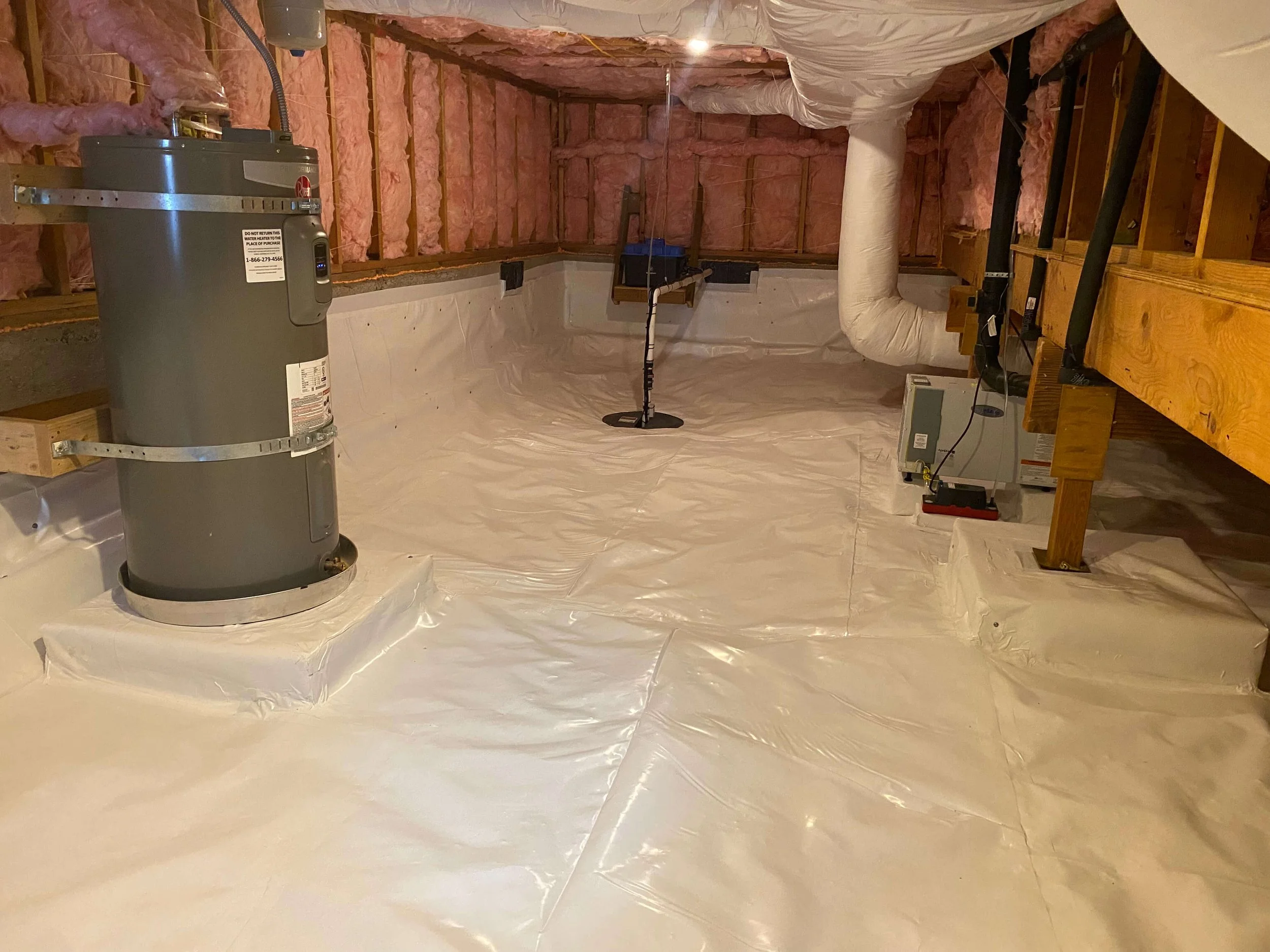 Unfinished basement with proper encapsulation. Showing ductwork, heating system, and insulation installed, with white plastic vapor barrier on the floor.