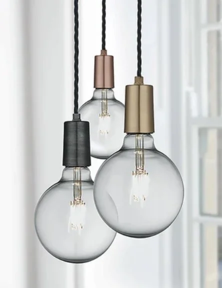 Three hanging light bulbs with black, gold, and copper-colored socket covers
