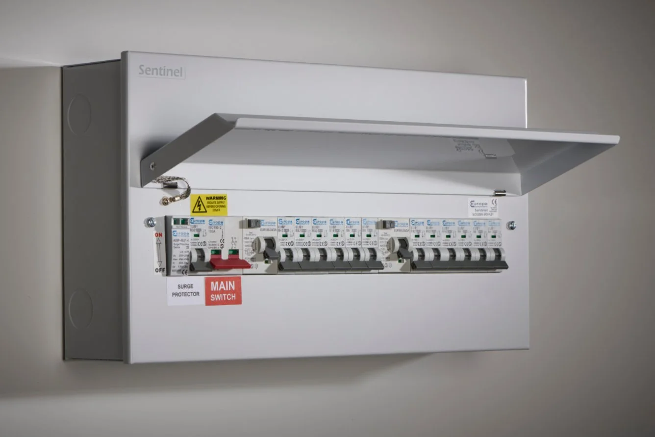 Electrical circuit breaker panel with a protective cover, labeled switches, and warning signs.