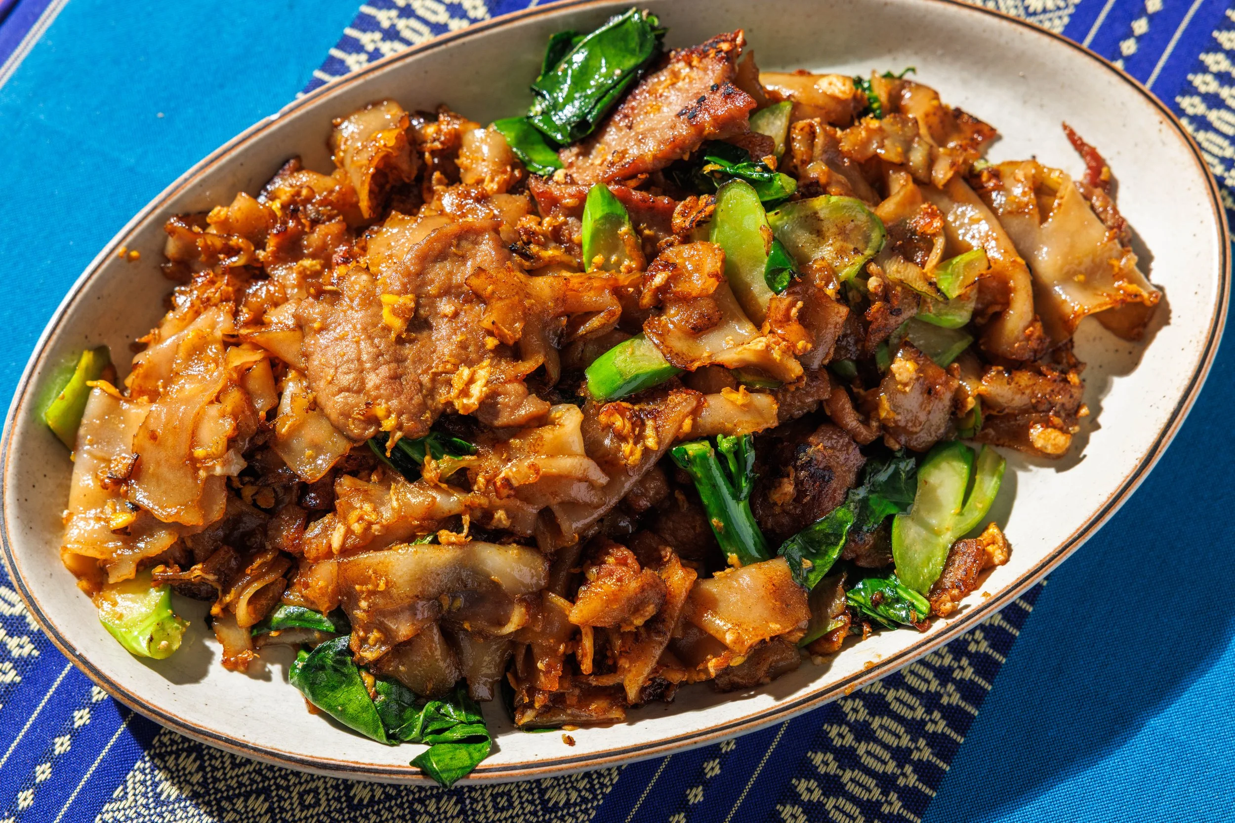 Stir-fried wide rice noodles with marinated pork shoulder, Chinese broccoli, egg & sweet soy sauce, white pepper.