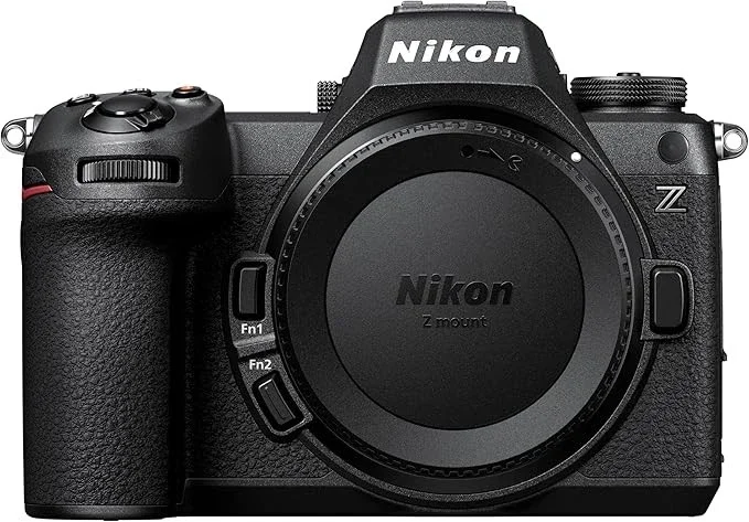 A black Nikon Z-series digital camera with a large lens mount but no lens attached. The camera features textured grip areas, control dials, and multiple buttons.