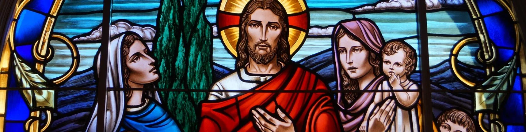 Colorful stained glass depiction of Jesus Christ with Mary and children.