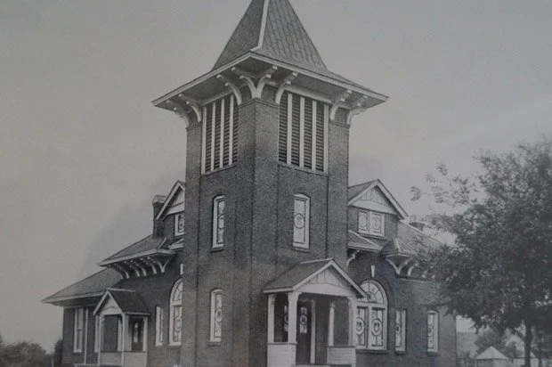 A tall, Victorian-style brick church with a steep, pointed roof and ornate windows.