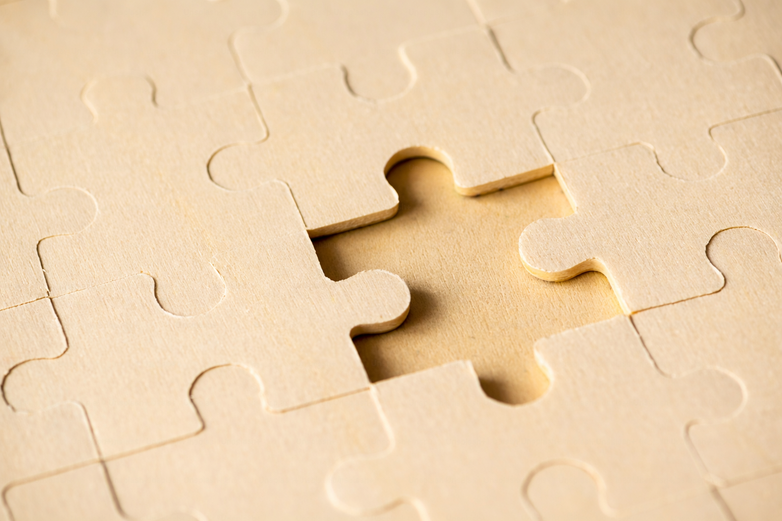 Close-up of a jigsaw puzzle with one piece missing, revealing the empty space.