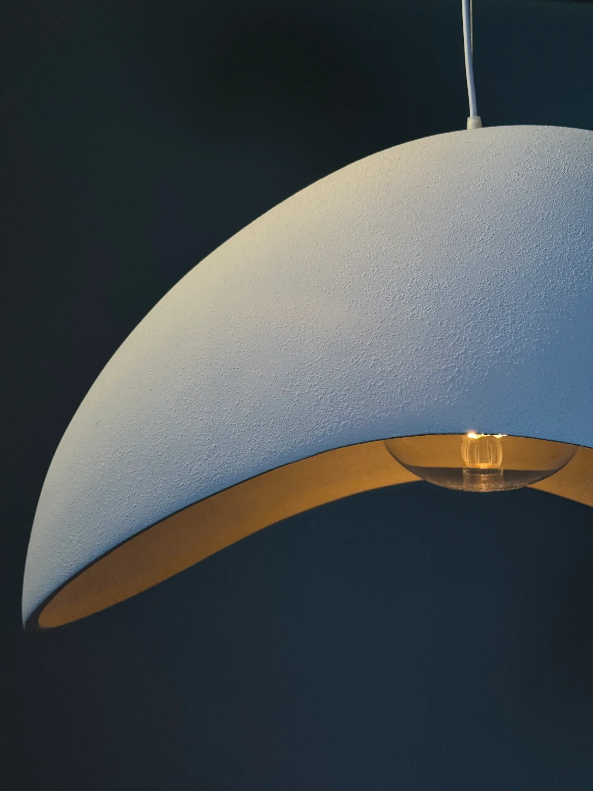 Suspension design Napoléon avec abat-jour incurvé blanc mat et ampoule apparente, luminaire moderne pour salon, salle à manger ou intérieur minimaliste.