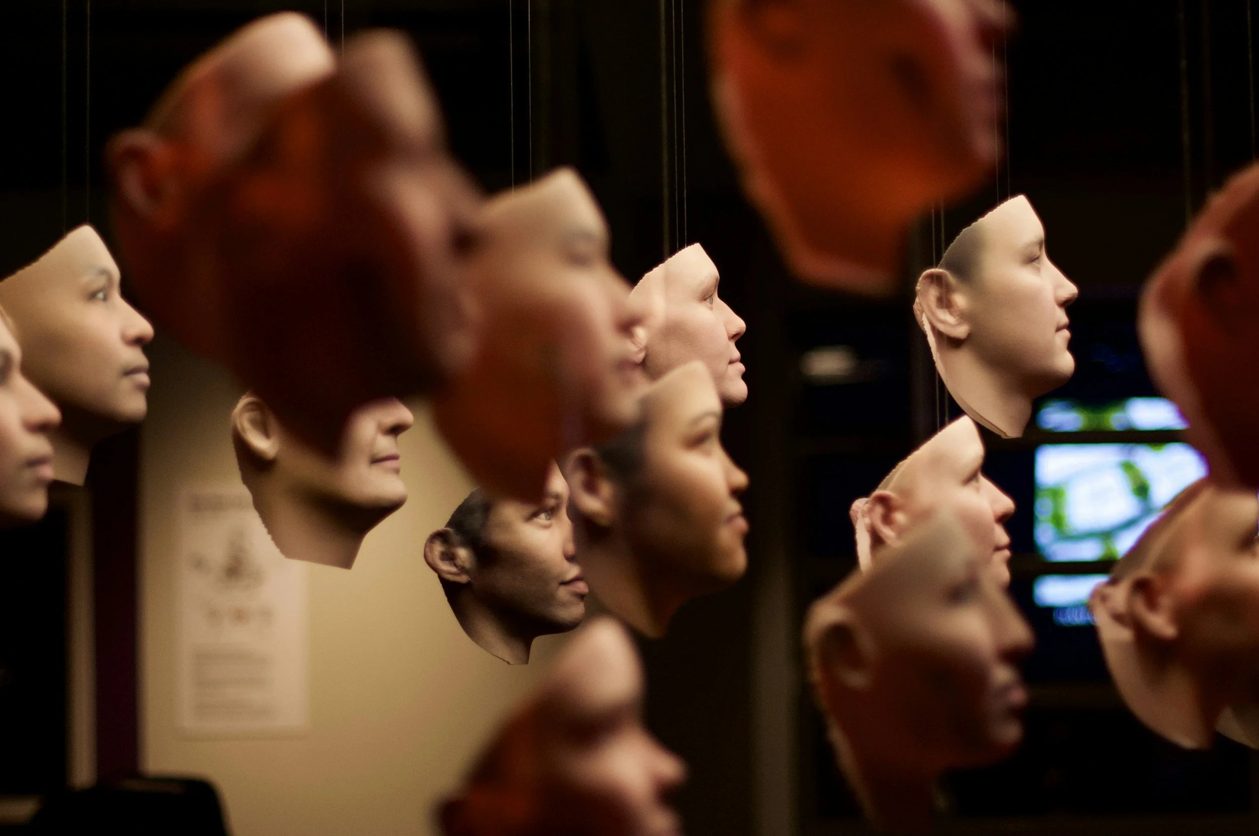 An audience of disembodied human like face masks as though floating in air all facing the same direction