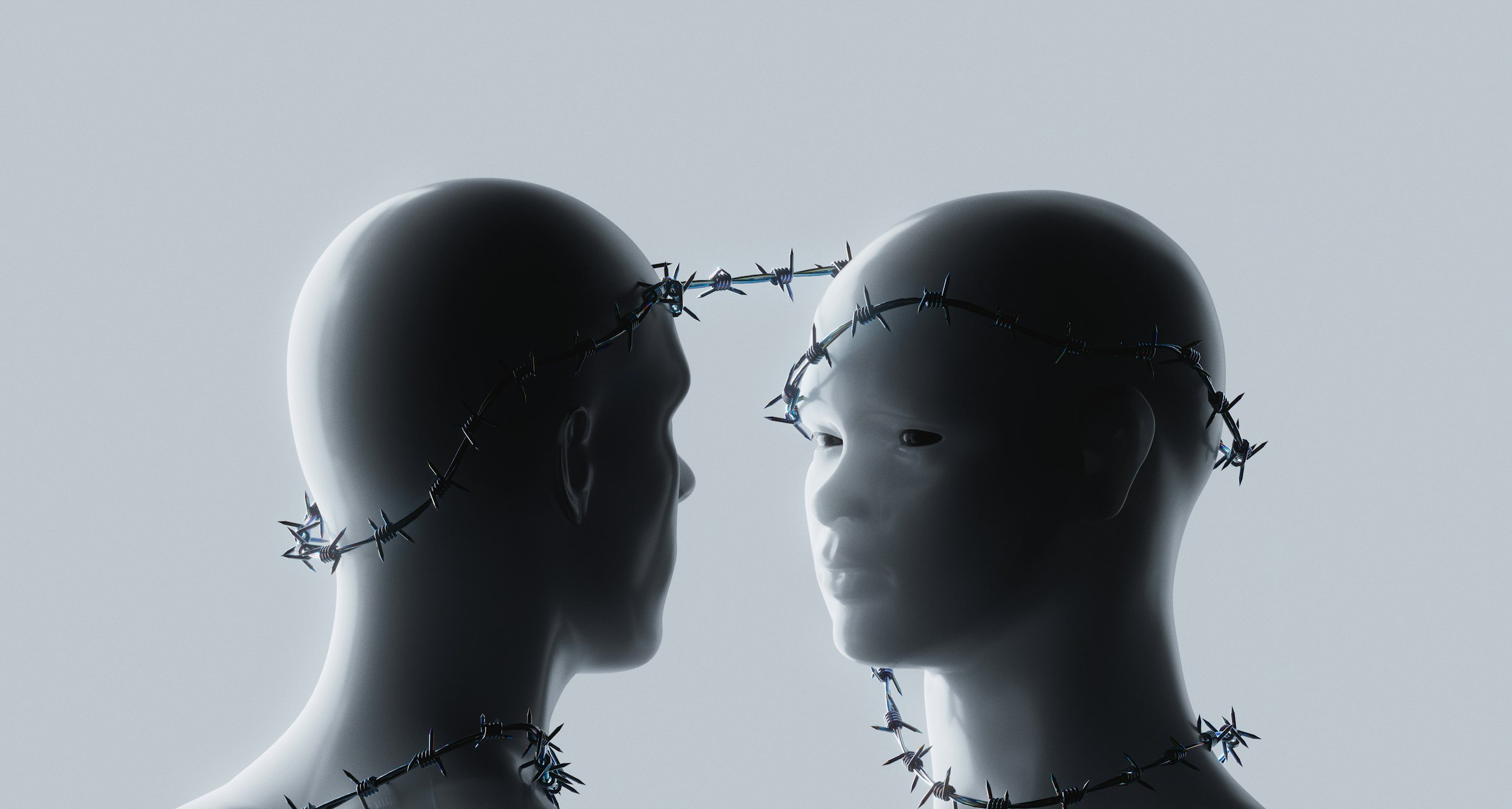 Two mannequin heads bound together with sharp barbed wire.