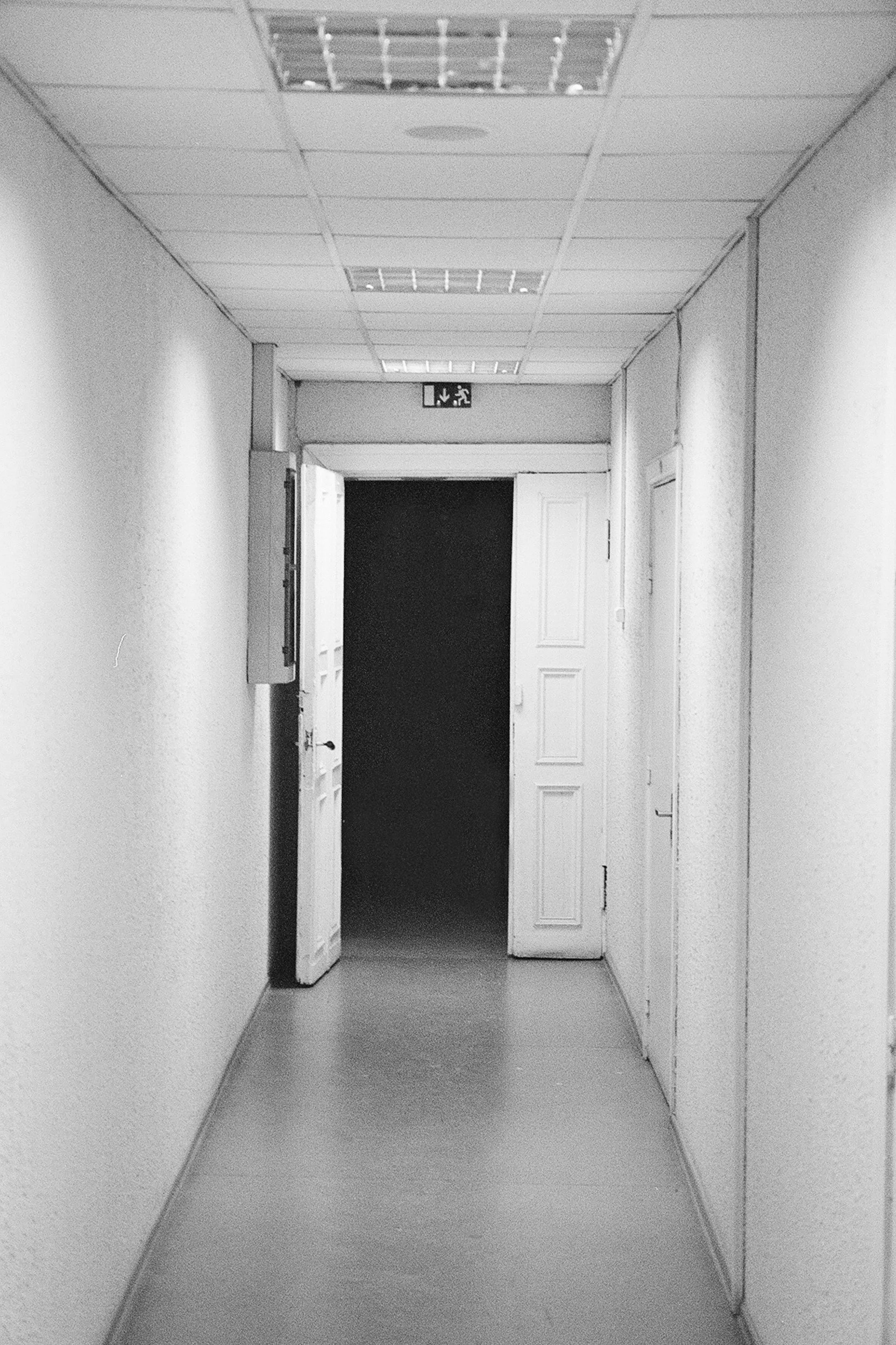 White clinical corridor leading to thick black darkness