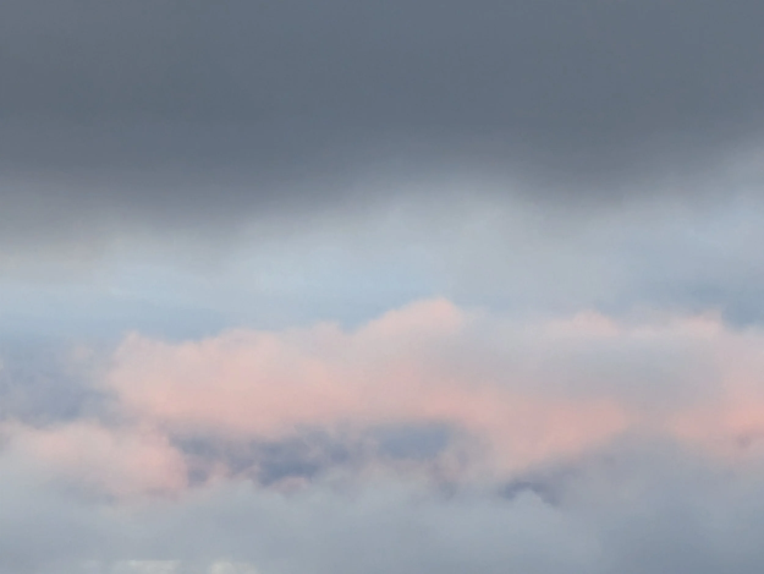A layered cloudscape with a heavy dark mass pressing down above a soft pink glow