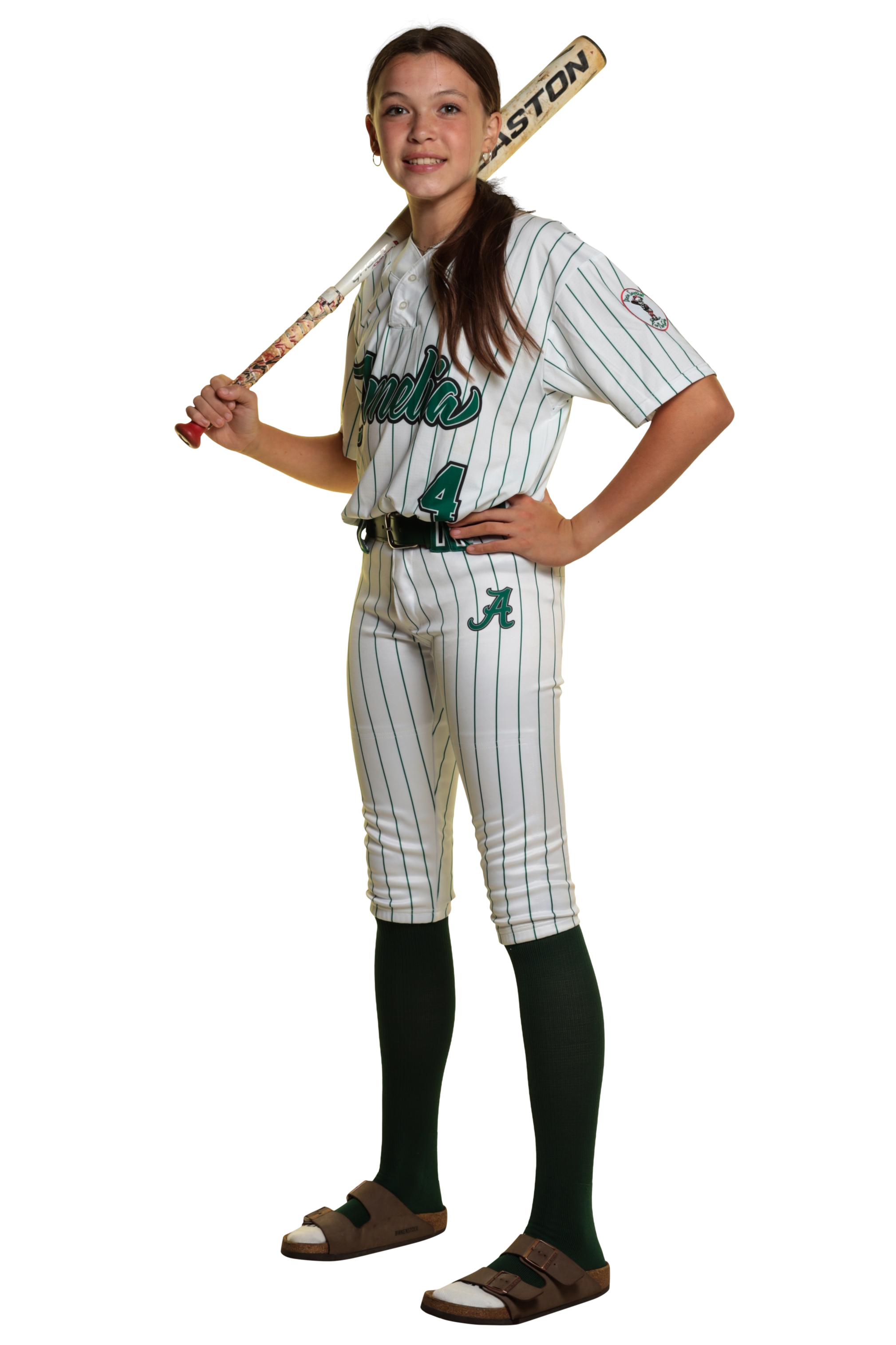 A young girl in a baseball uniform holding a bat over her shoulder, standing confidently with her hand on her hip.