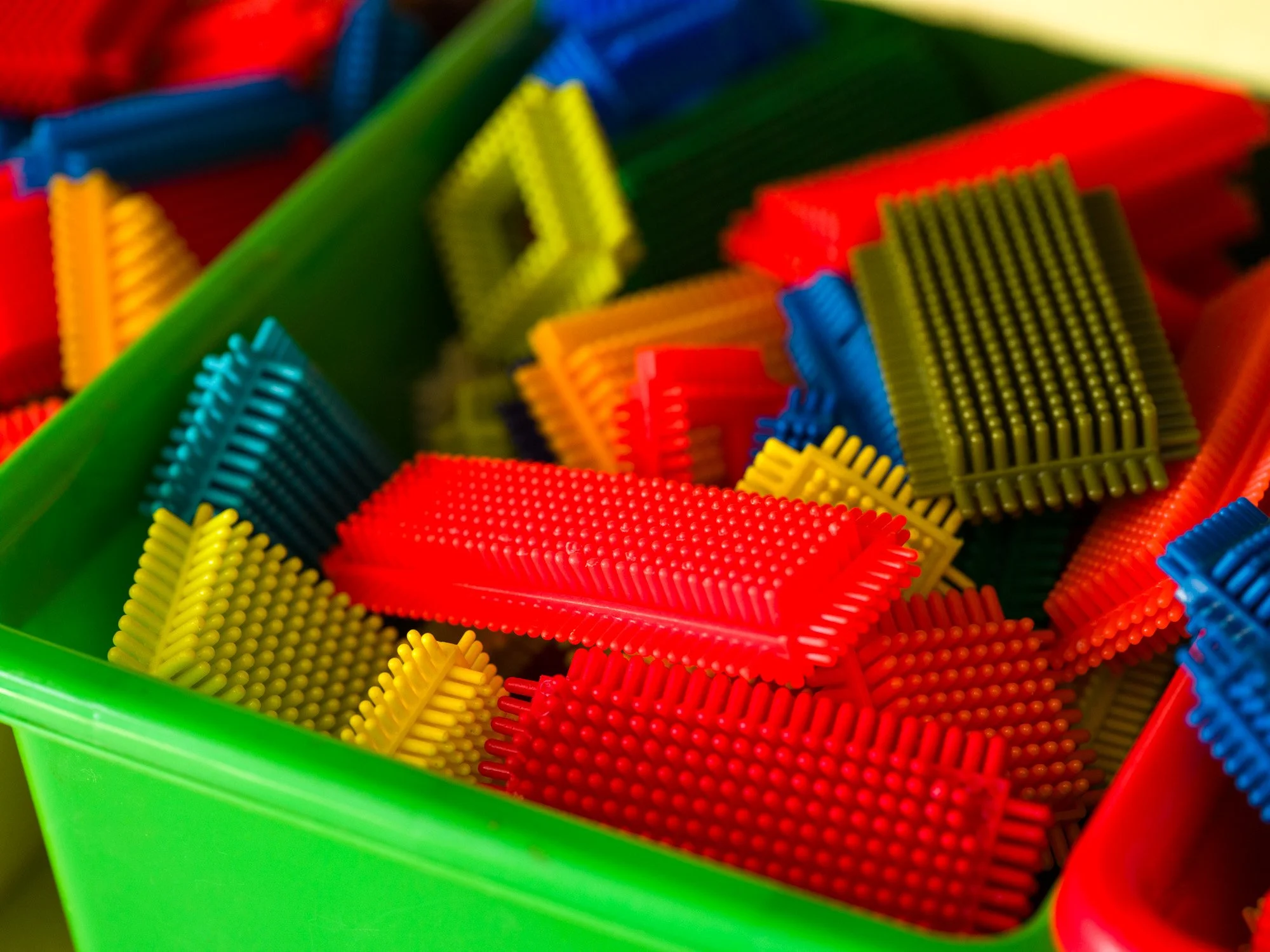 Colorful plastic domino pieces with textured surfaces, arranged in a container.