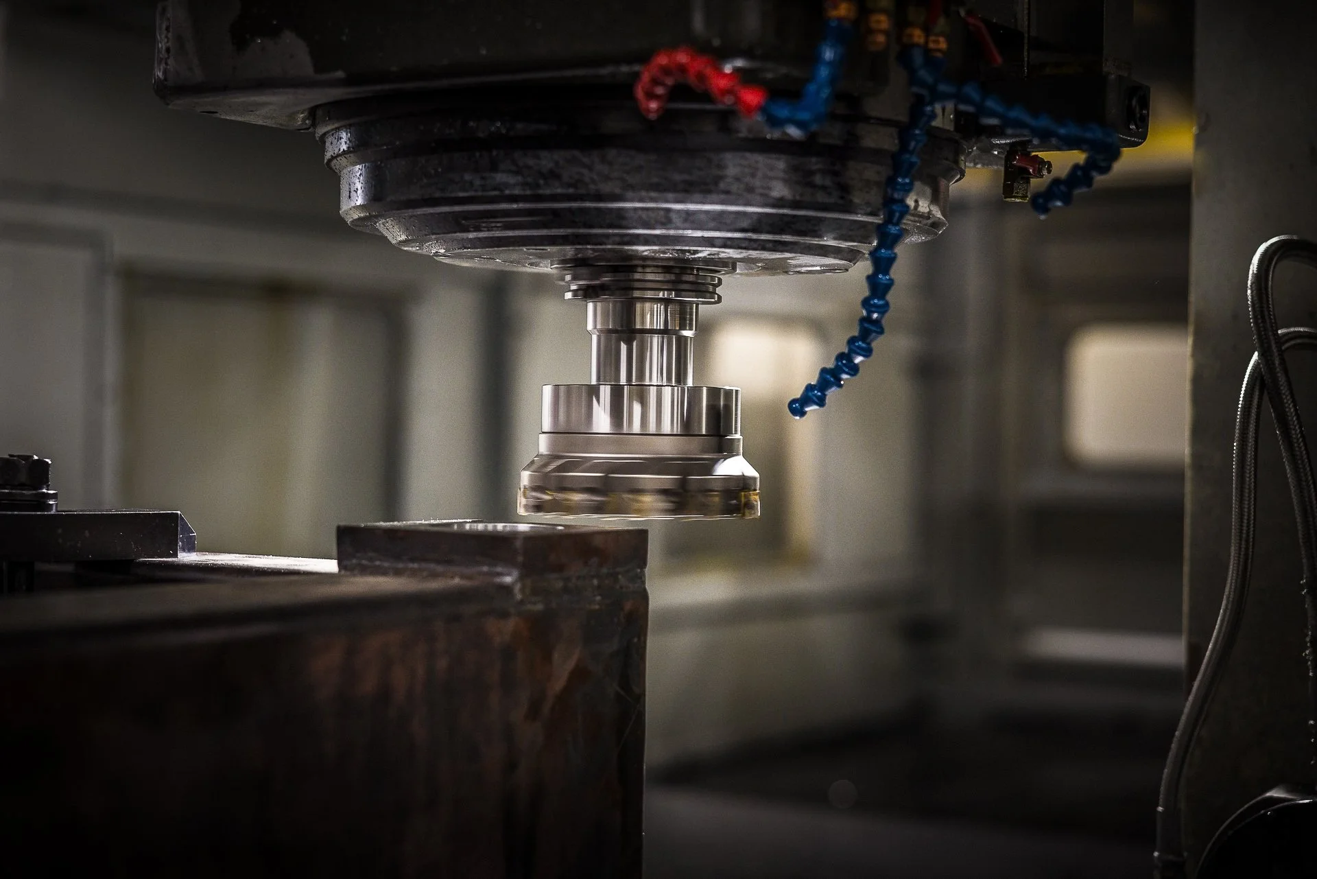Close-up of a CNC machine milling a metal workpiece, with cutting tools and coolant hoses visible.