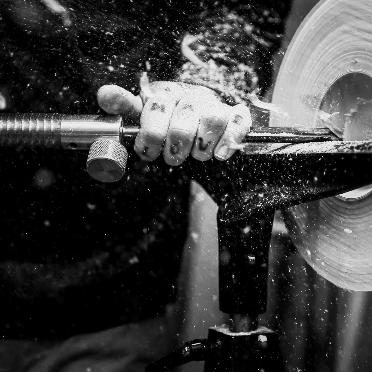 A person using a hand-held electric saw to cut wood, with sawdust flying around.