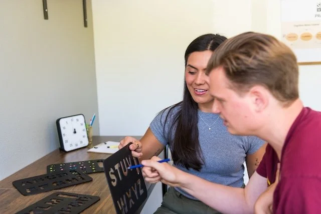 A provider and speller working together on a letterbaord, in an office or classroom setting.
