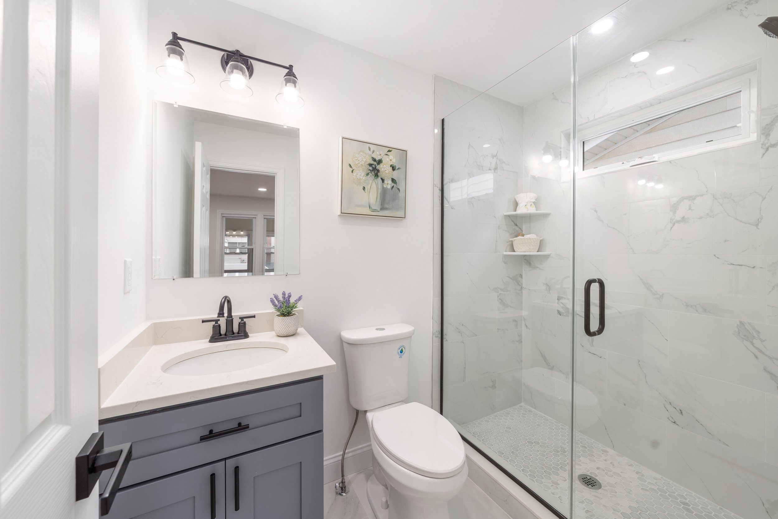 Bathroom with vanity, mirror, toilet, and walk-in shower with marble tiles