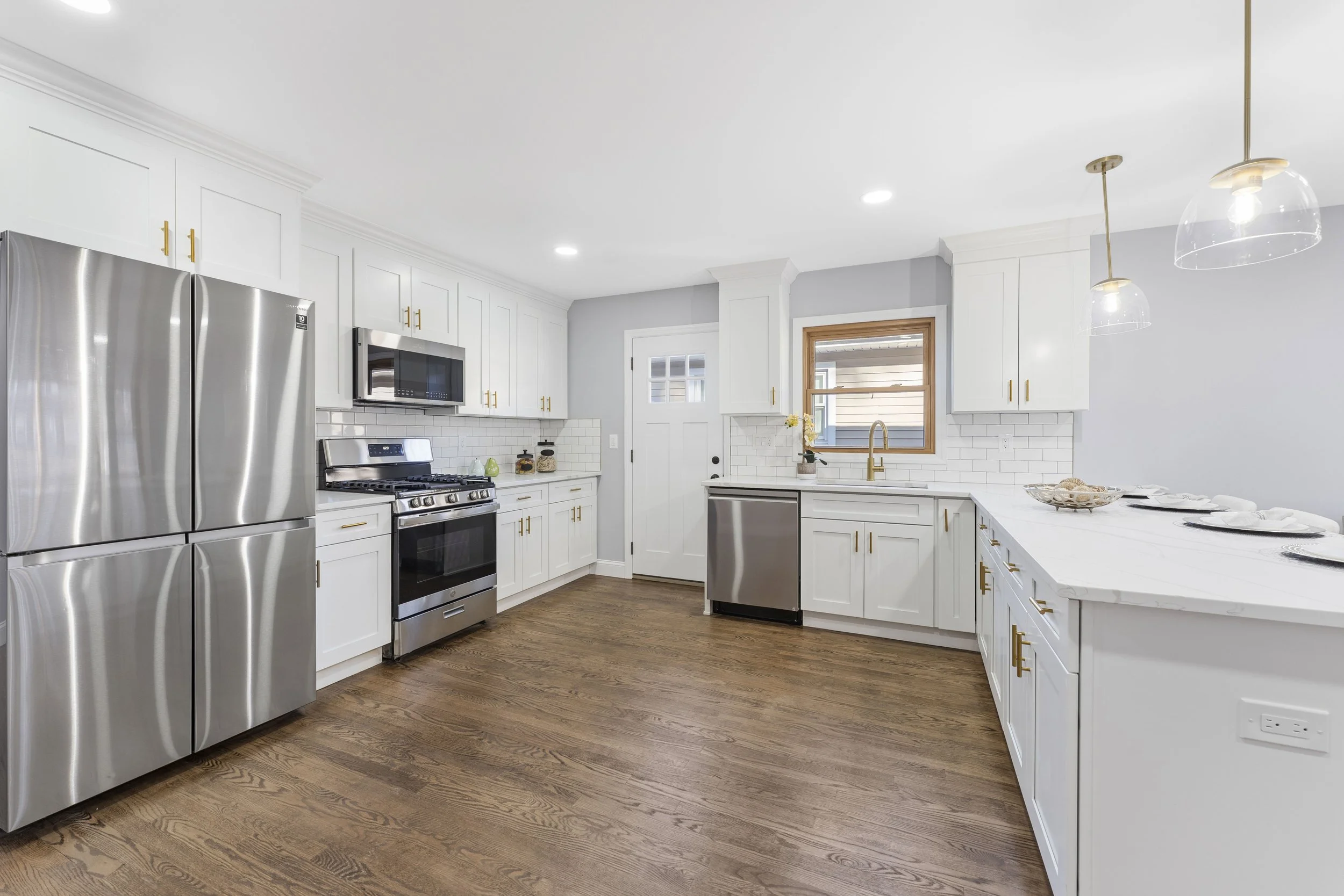 Modern kitchen with white cabinetry, stainless steel appliances, and hardwood floors.